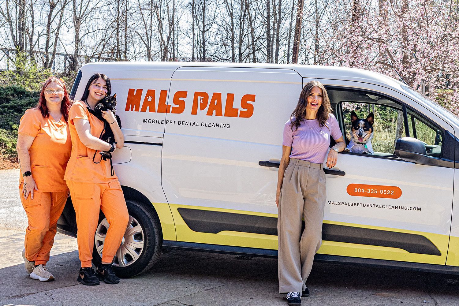 Three women and a dog by a van. 