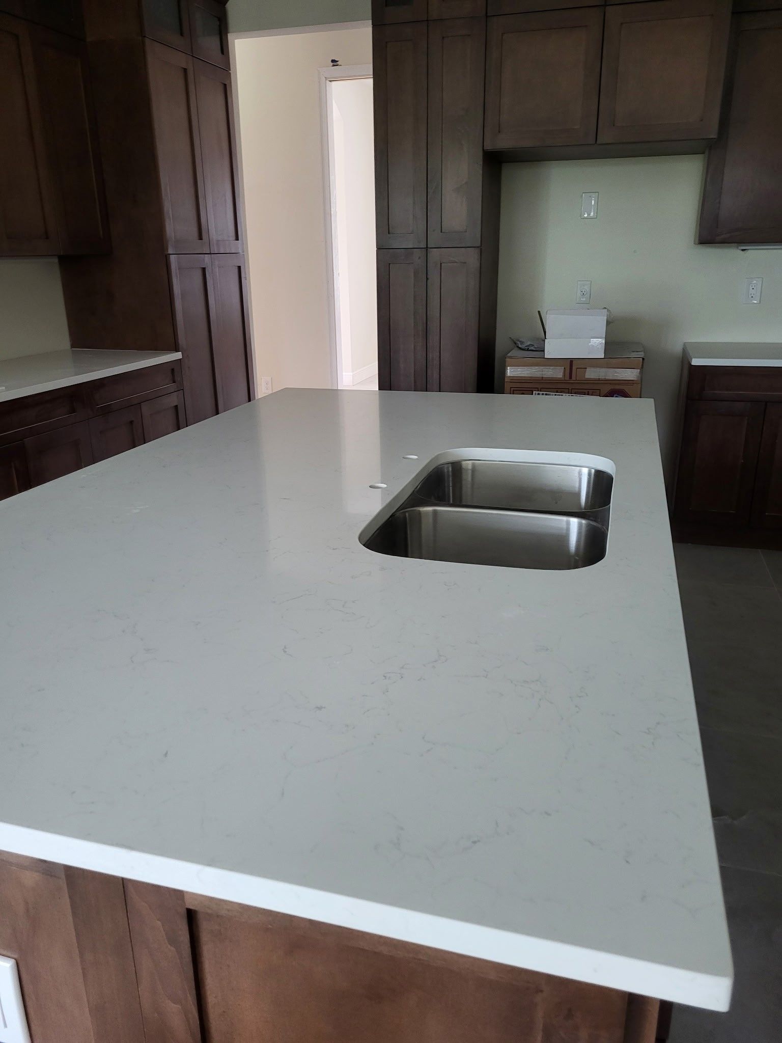 A new kitchen island with a light-colored countertop and a sink cutout, brown cabinets in the background.