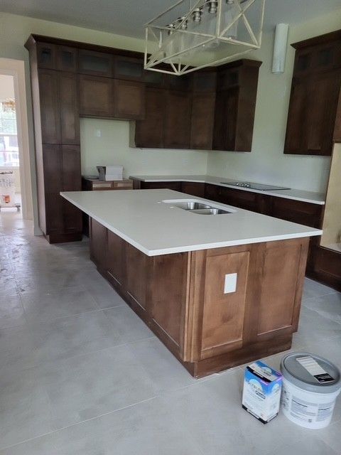 Kitchen with dark brown cabinets, white countertops, and an island. Gray concrete floor.