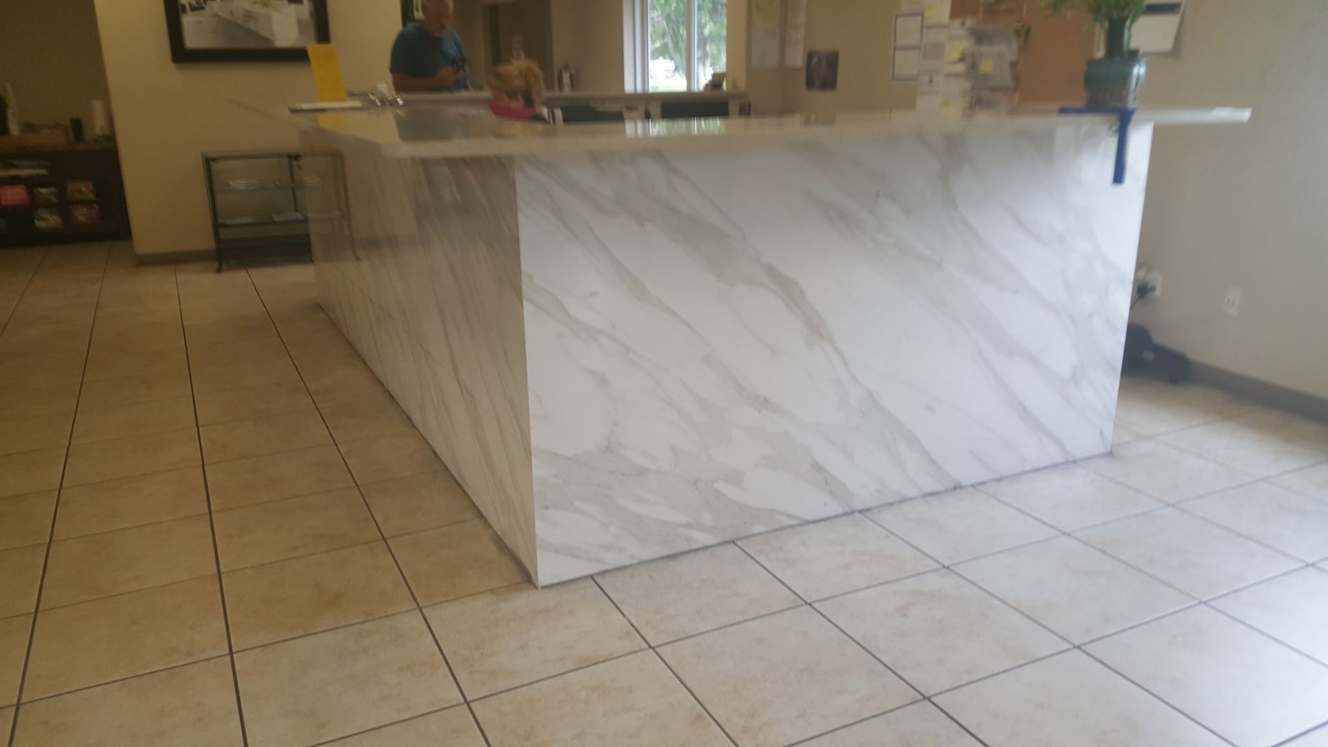 Reception desk with marble-like finish, tan tiled floor.