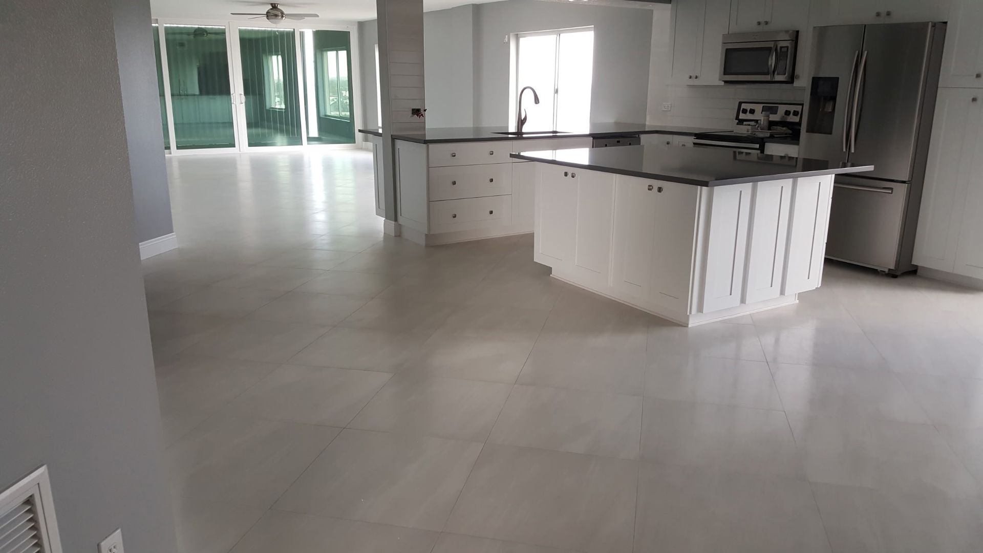 spacious modern kitchen with white cabinets, dark countertops, and stainless steel appliances