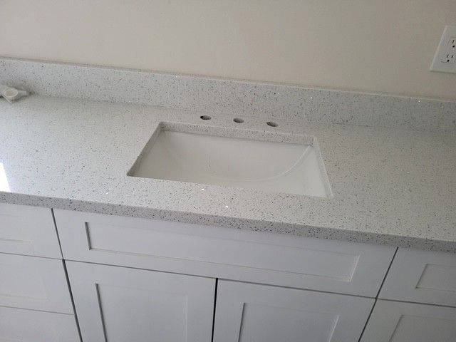 white bathroom vanity with speckled countertop and rectangular sink