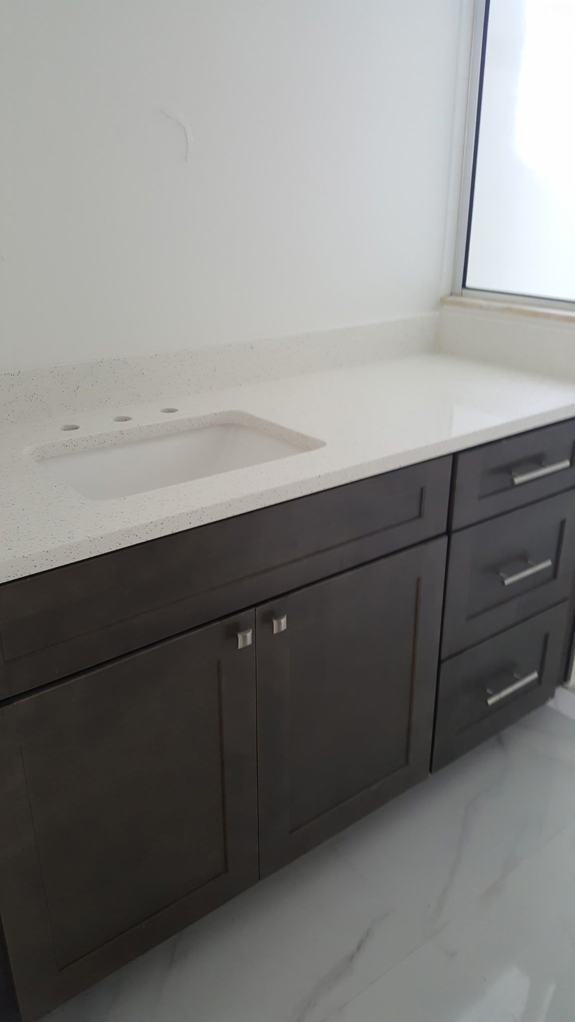 dark brown bathroom vanity with white countertop, sink, and drawers
