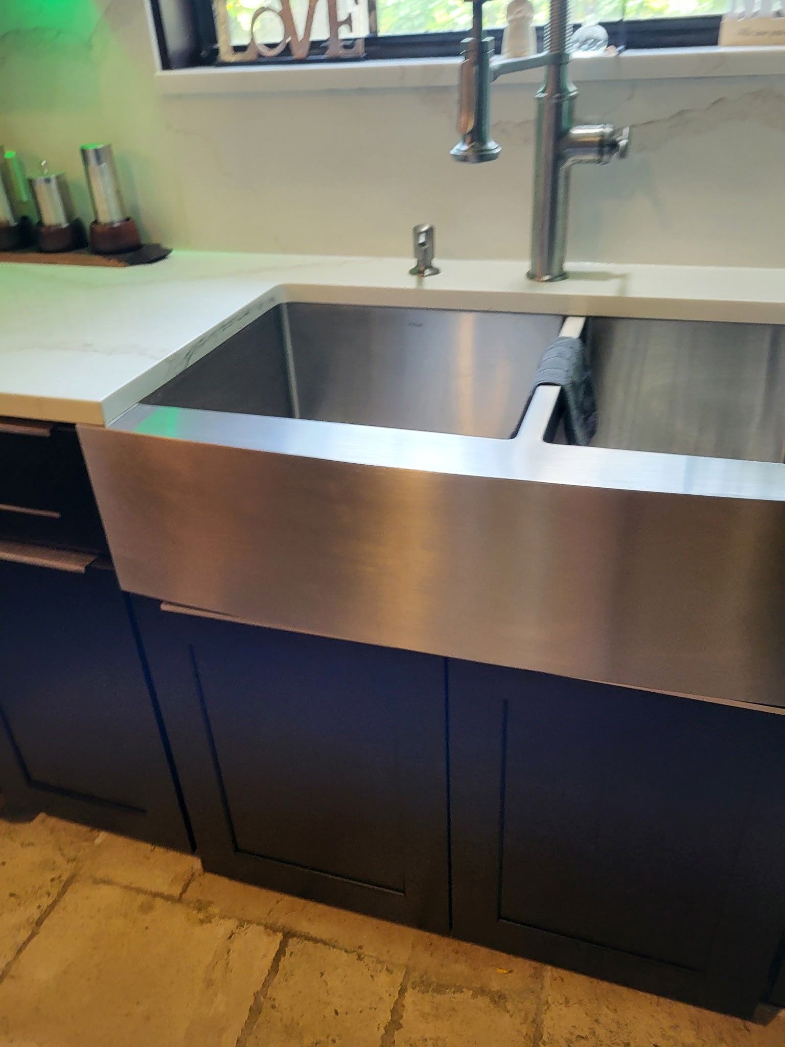 stainless steel kitchen sink in front of dark cabinets and light countertop