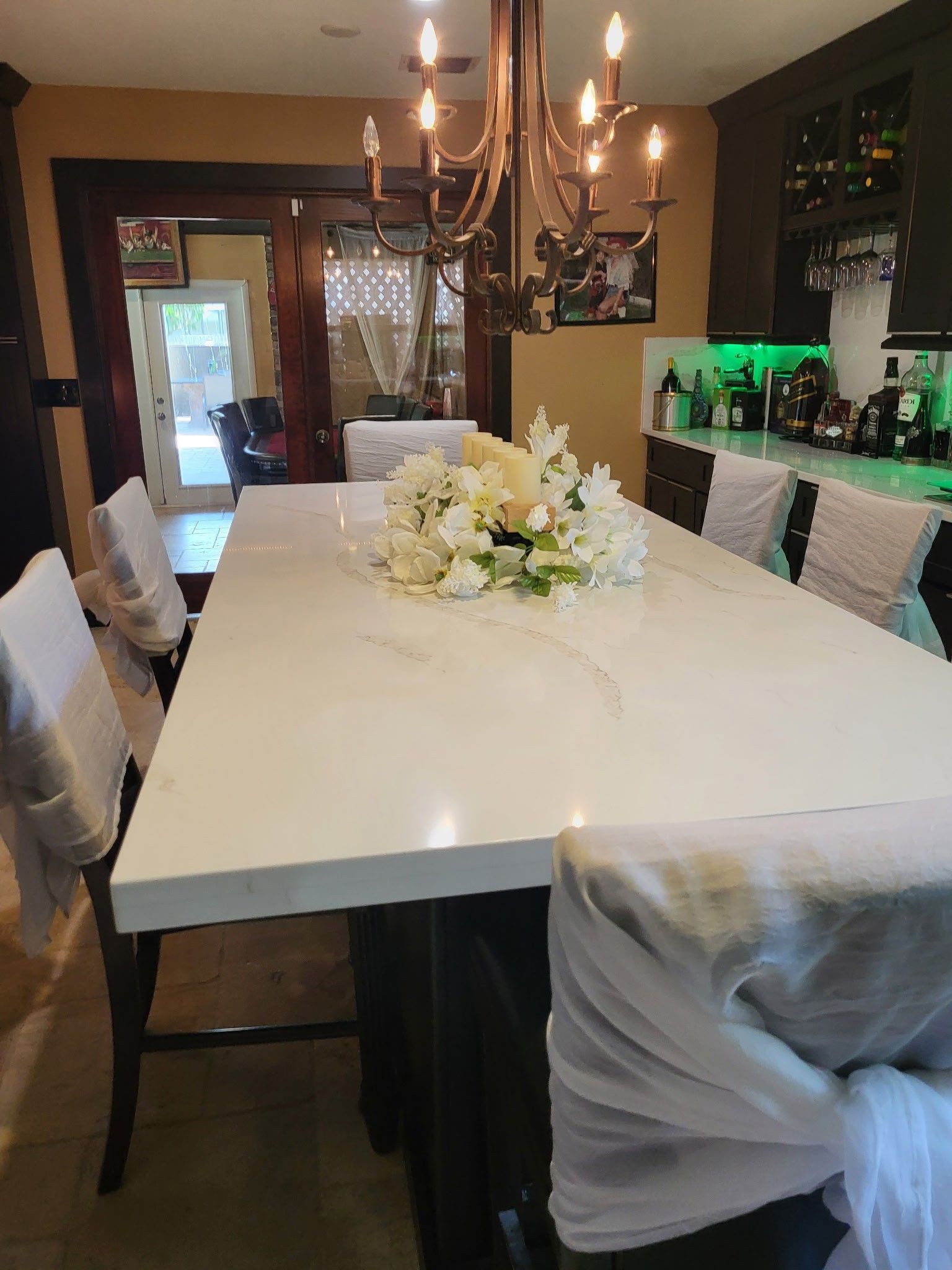 dining room with a long white table, chairs with white covers, and a floral centerpiece