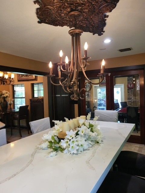 dining room with chandelier, long white table with floral arrangement, brown walls