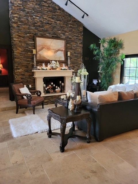 living room with stone fireplace, leather sofa, and dark wood furniture