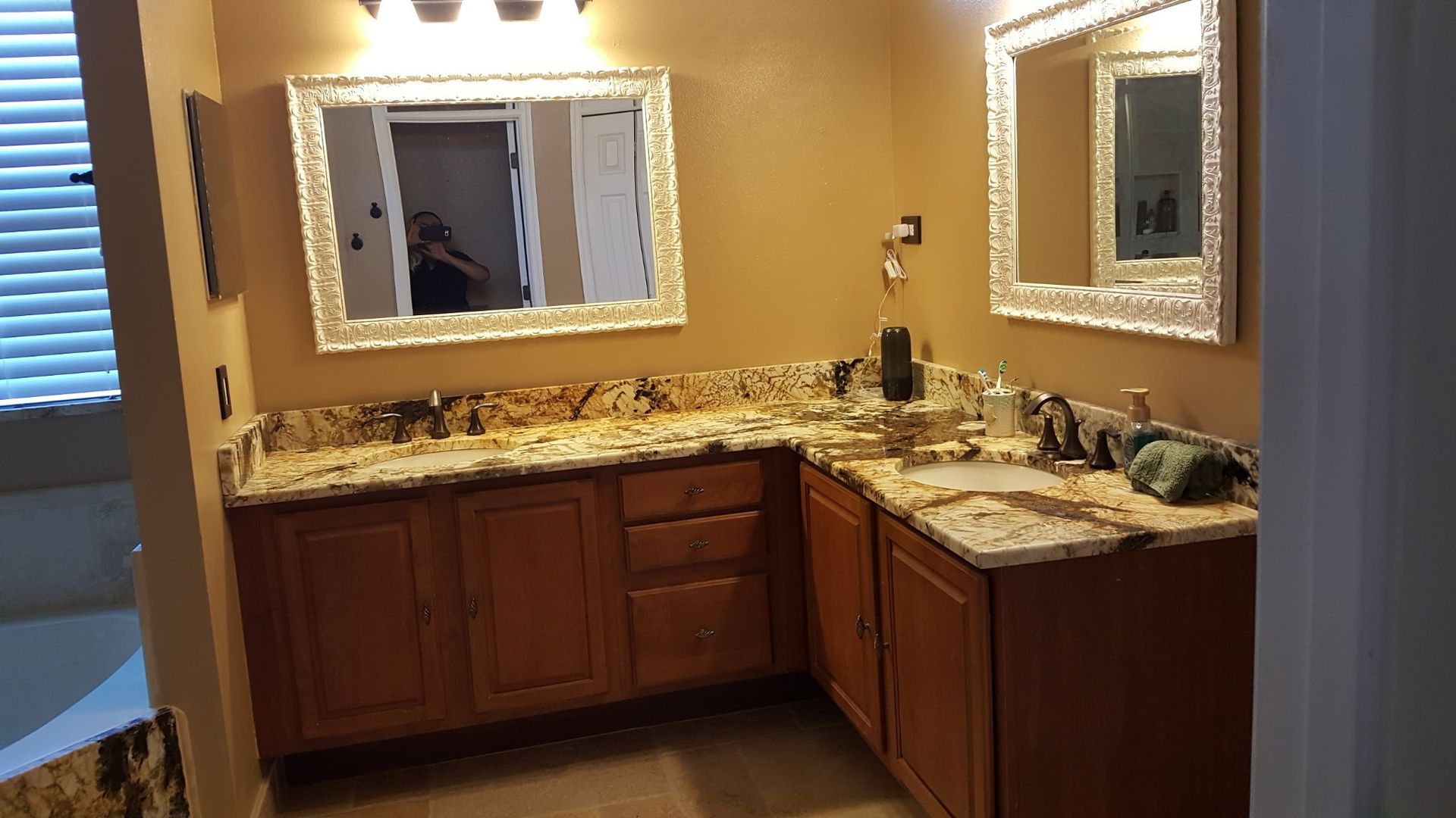 bathroom with wood cabinets, two sinks, granite countertop, and ornate mirrors