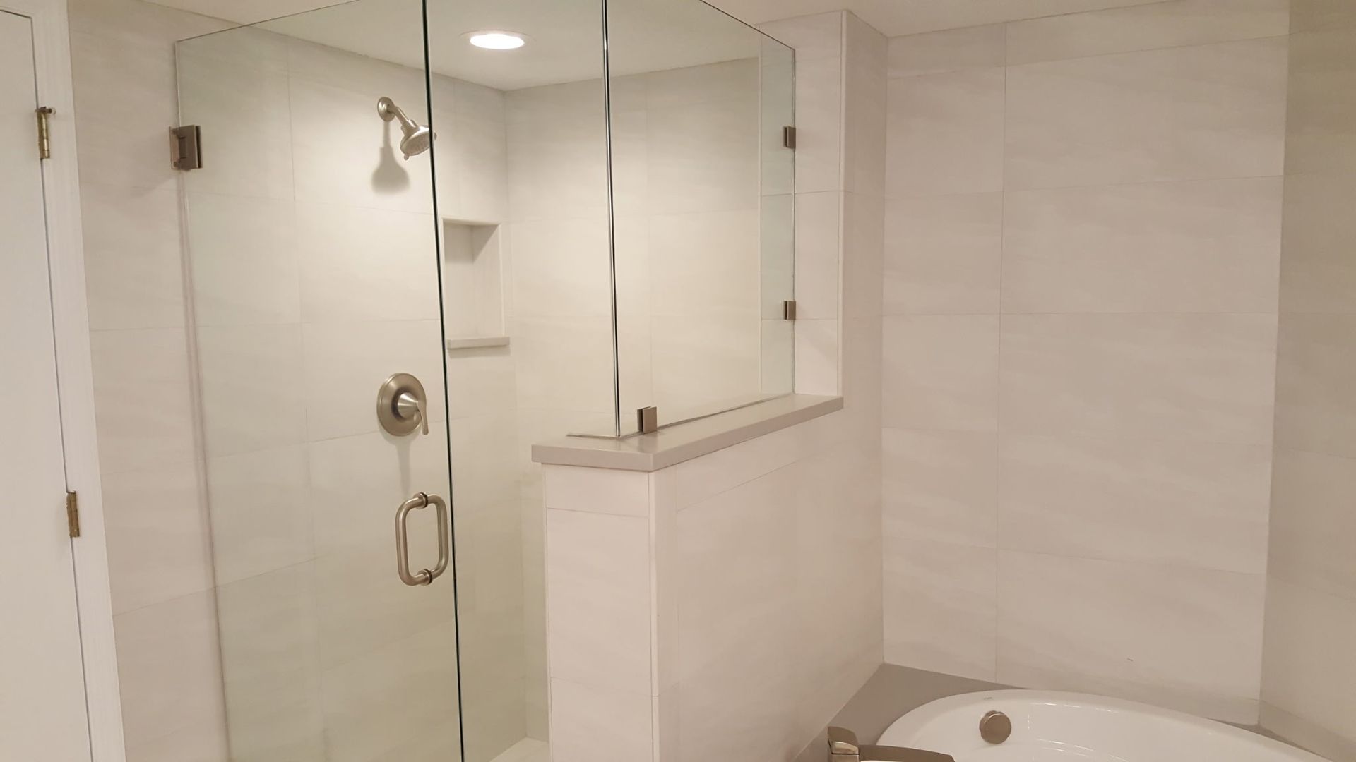 modern white bathroom with a glass shower, bathtub, and light gray accents