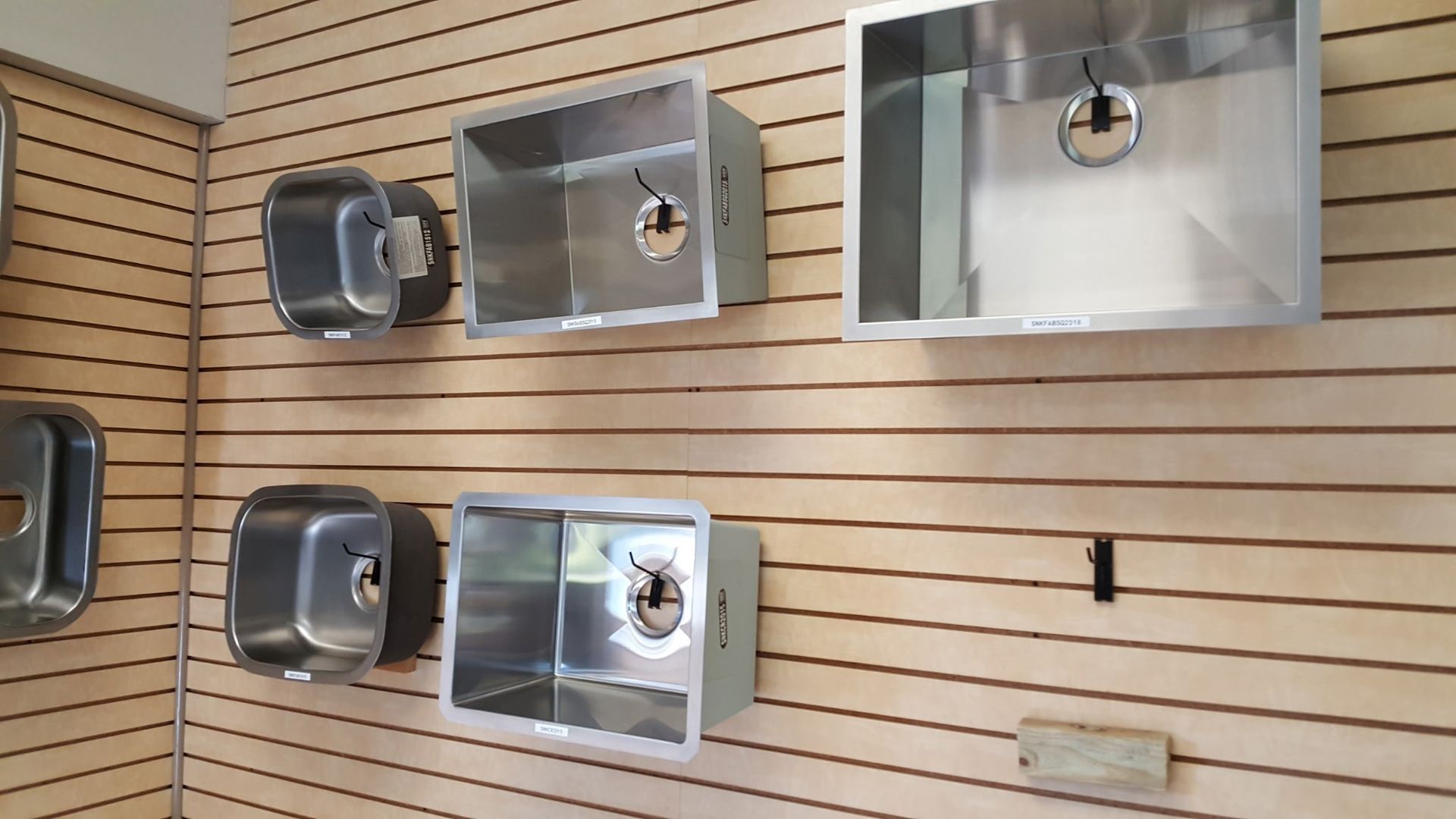 stainless steel sinks on a wood slat wall display in a store