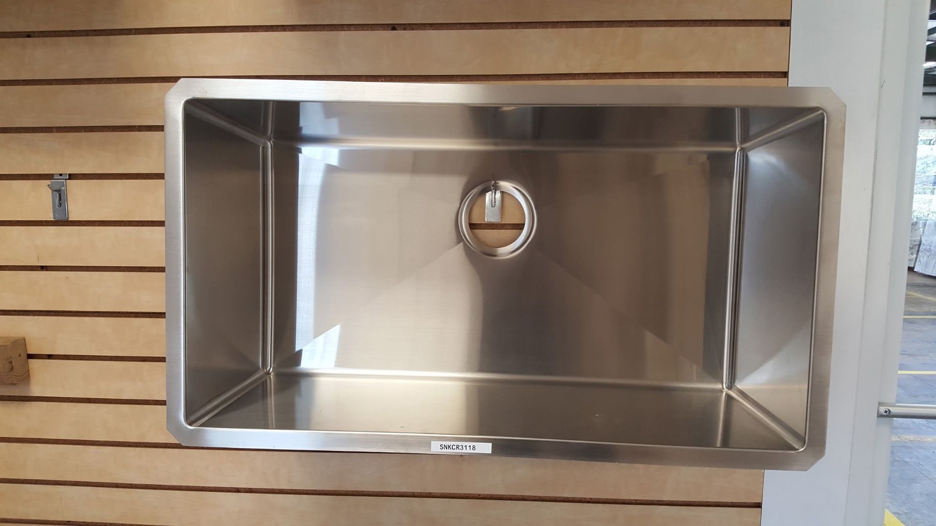 stainless steel kitchen sink, rectangular shape, mounted on wood paneling, drain hole centered