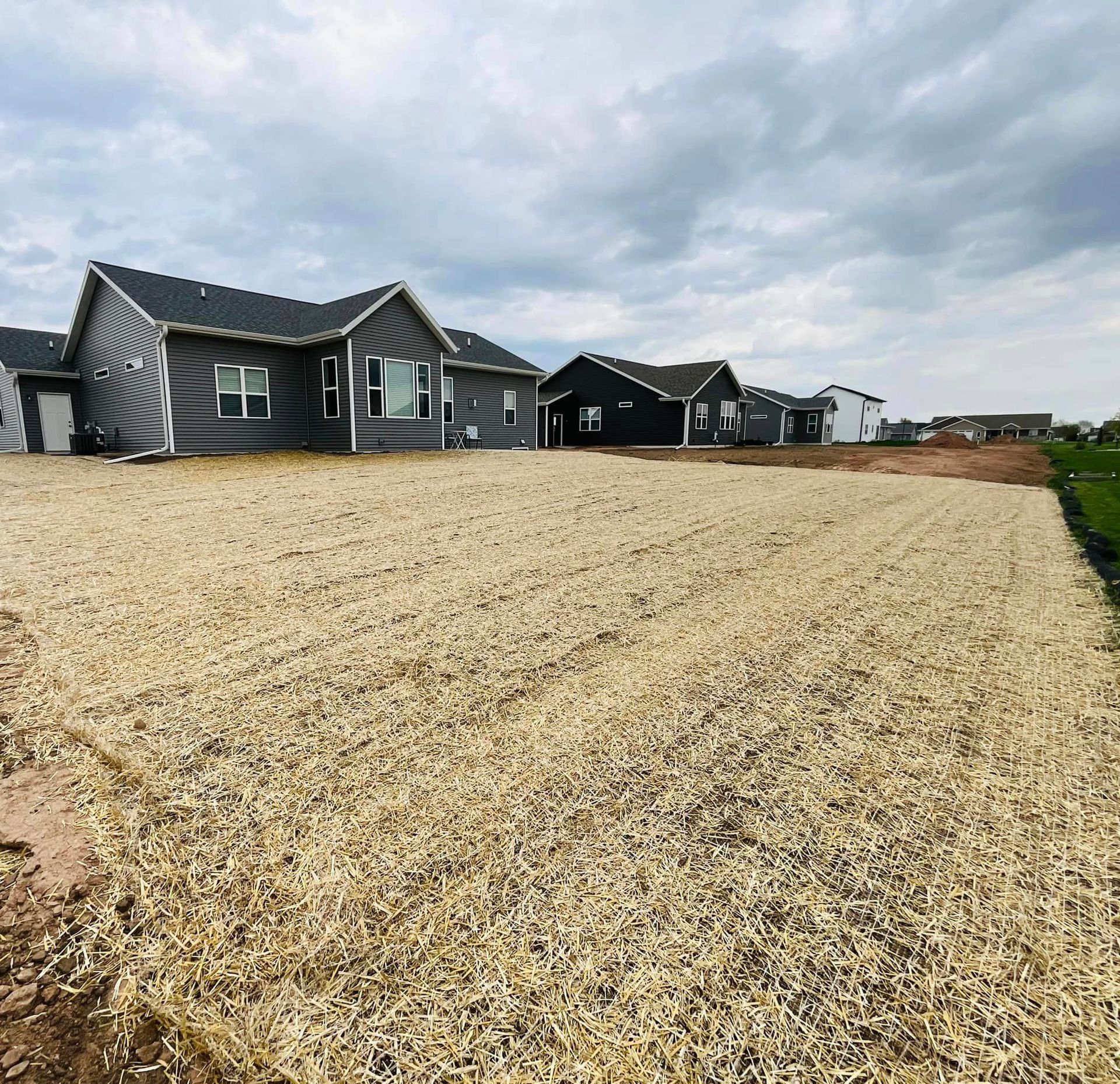 A row of houses are sitting on top of a lush green field.