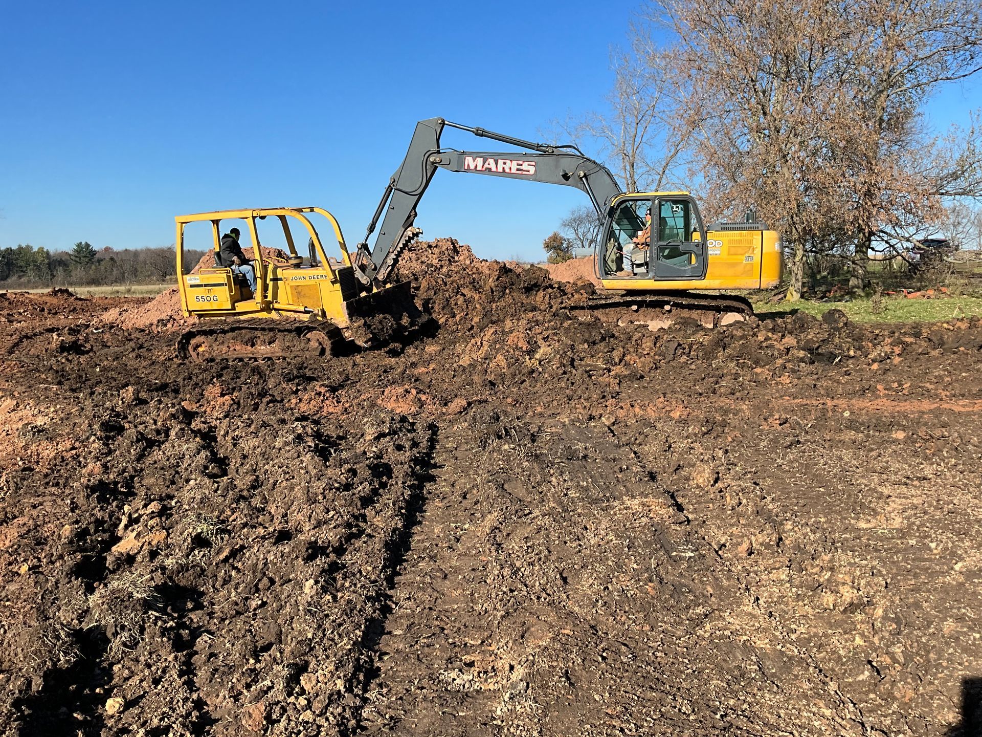 A yellow excavator is moving dirt in a field.