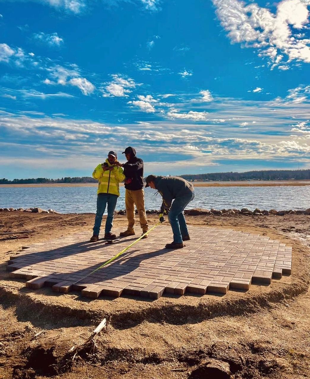 A group of people are standing on top of a brick platform next to a body of water.