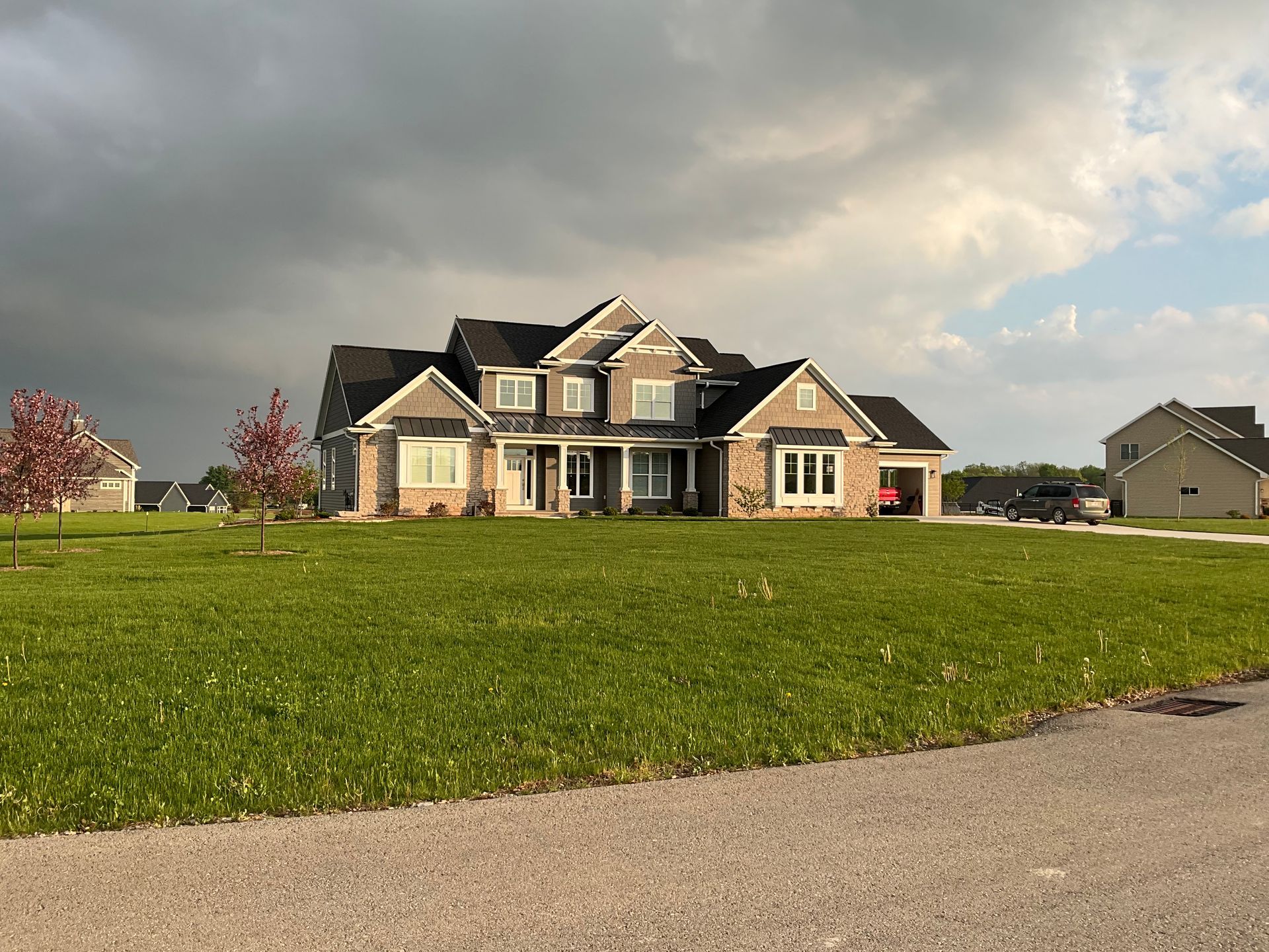 A large house is sitting in the middle of a lush green field.