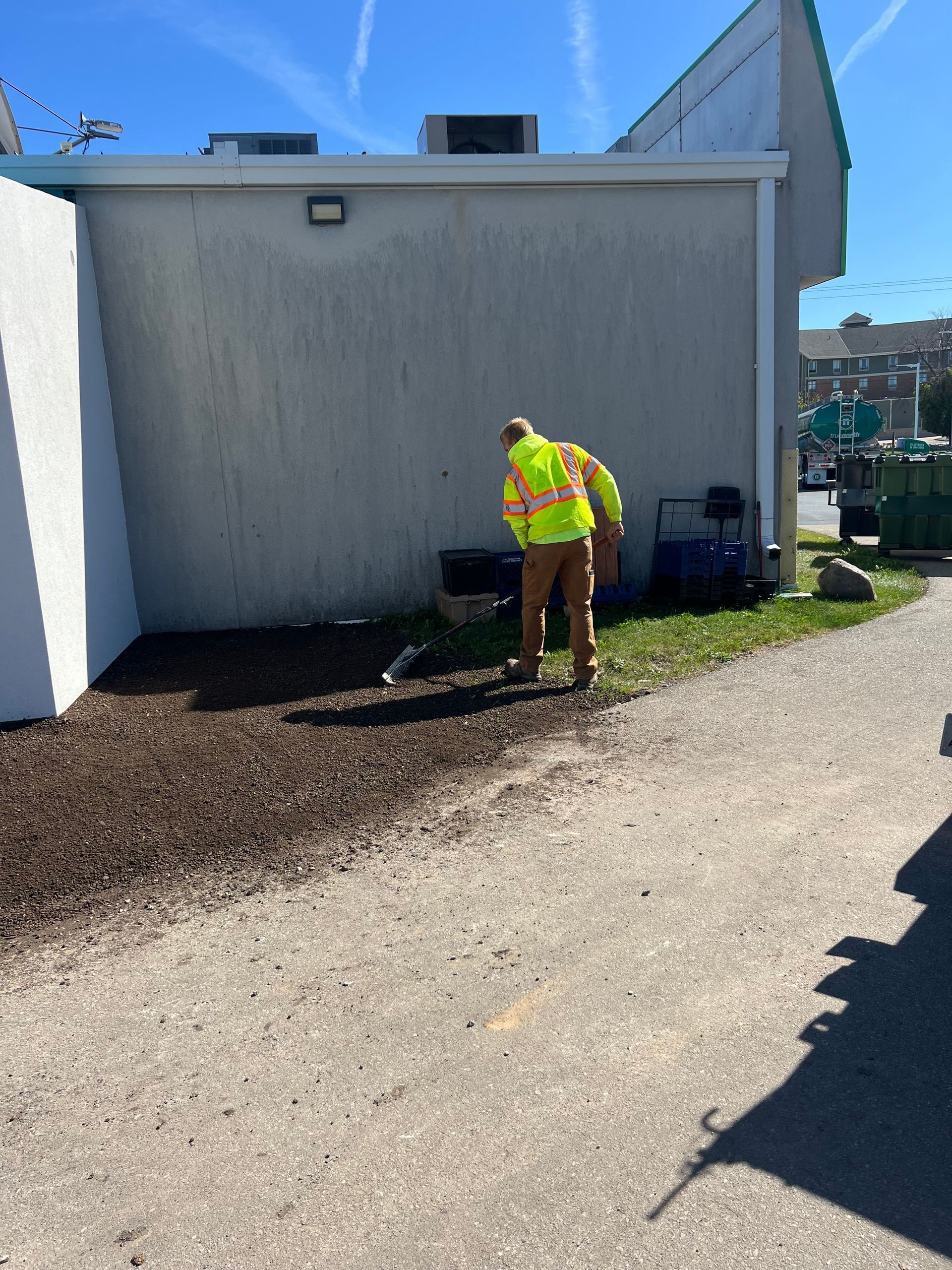 A man in a yellow safety vest is digging in the dirt