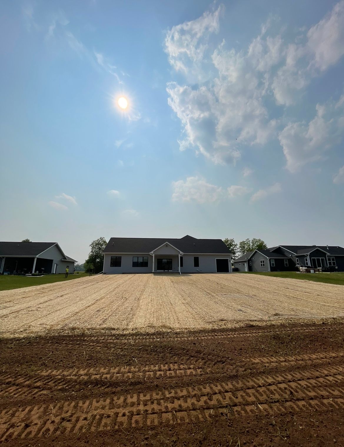 A house is sitting in the middle of a dirt field.