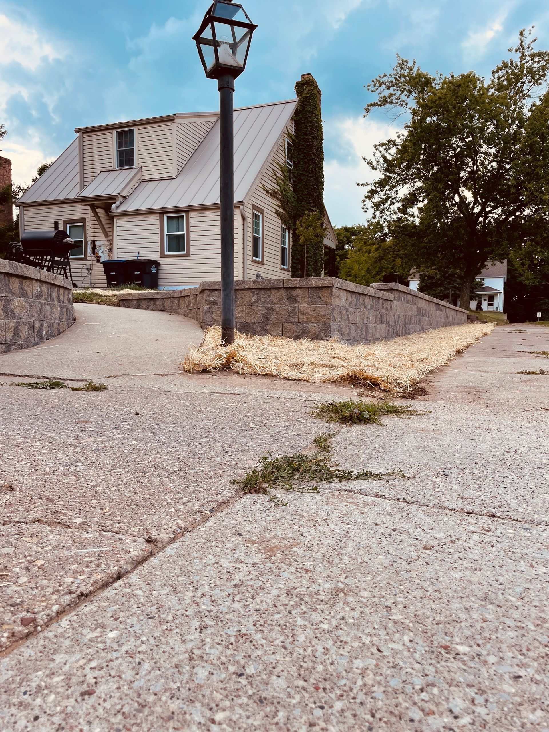 A street light in front of a house on a gravel road