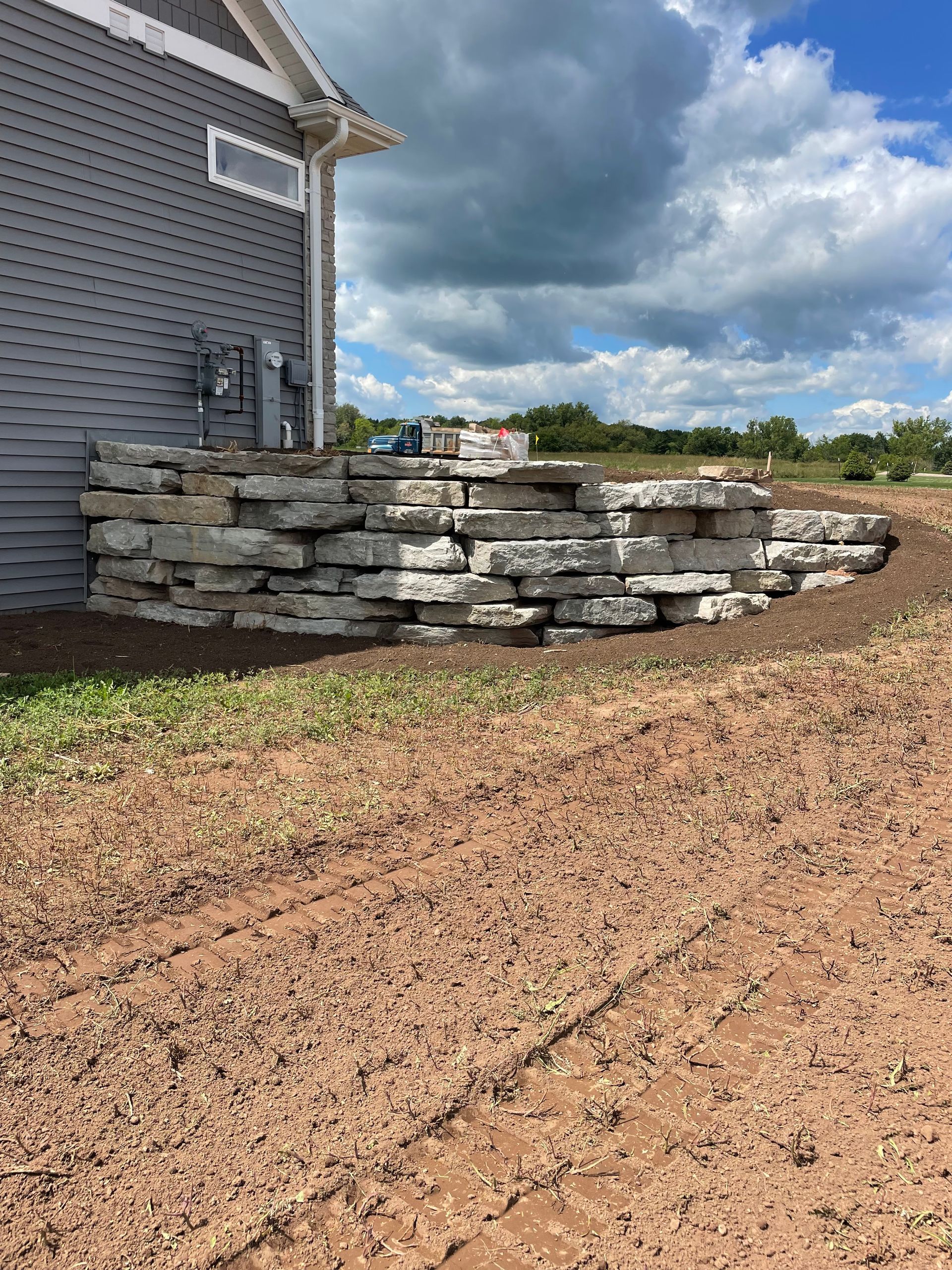 A stone wall is being built in front of a house.