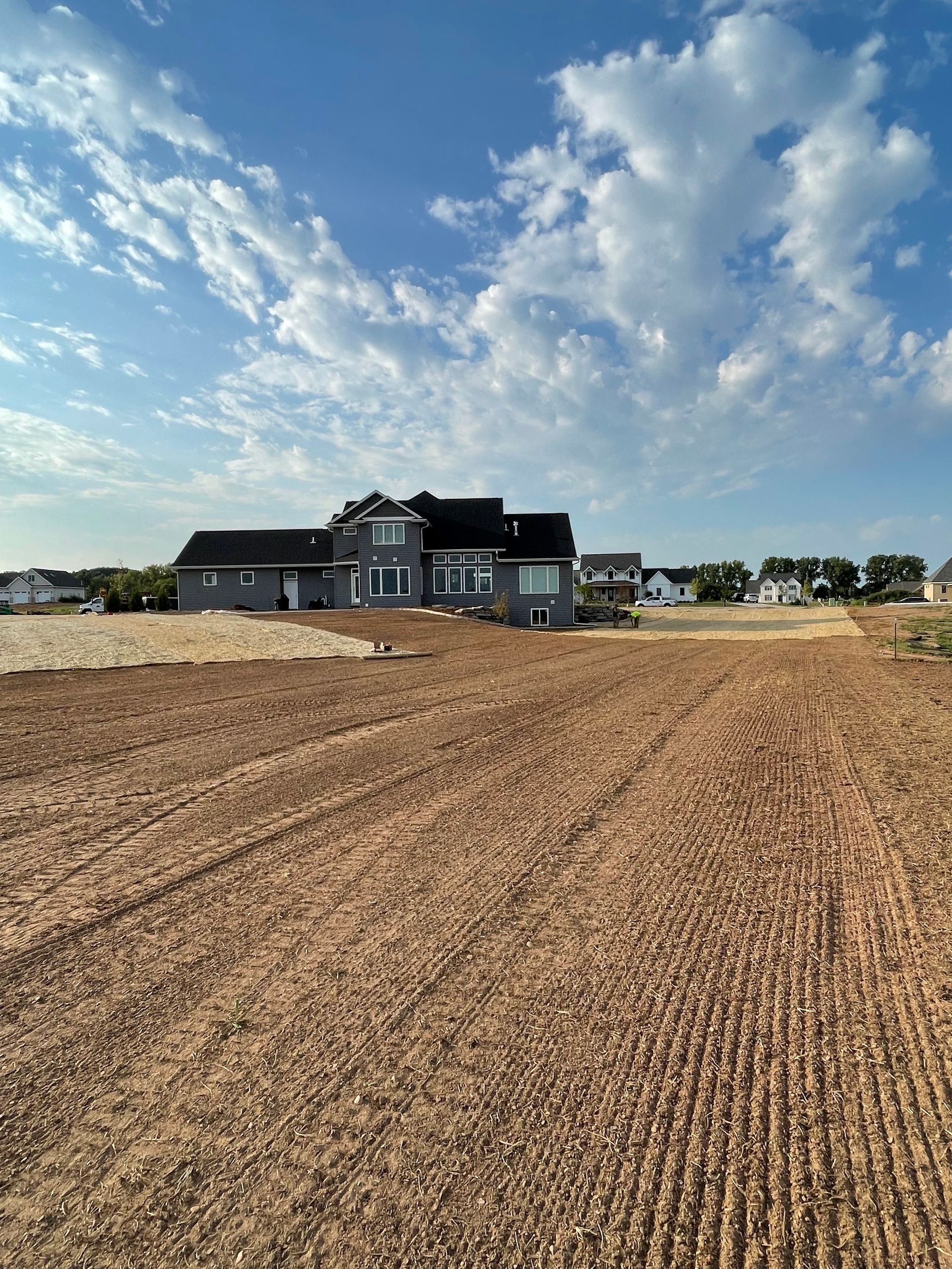 A large house is sitting in the middle of a dirt field.