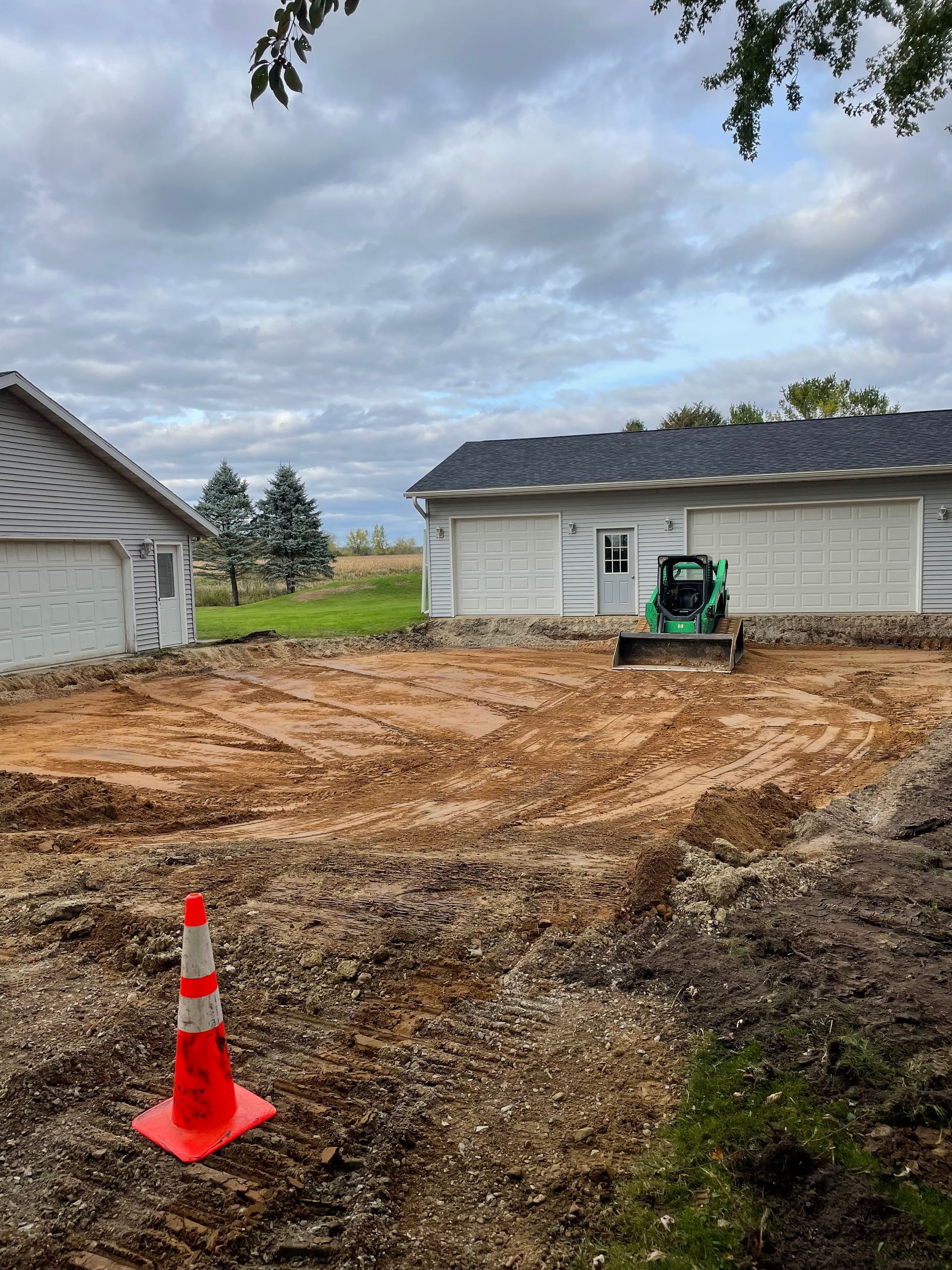 A green bulldozer is moving dirt in front of a house.