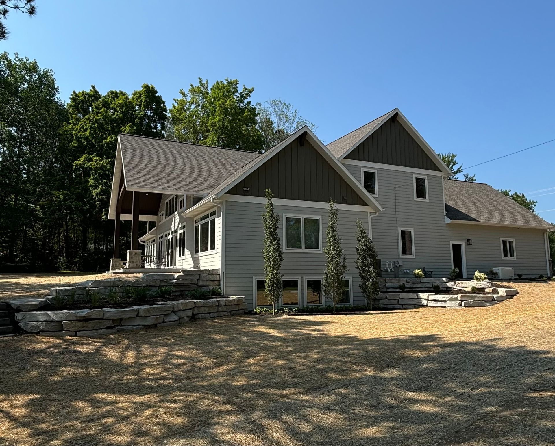 A large white house with a brown roof is surrounded by trees
