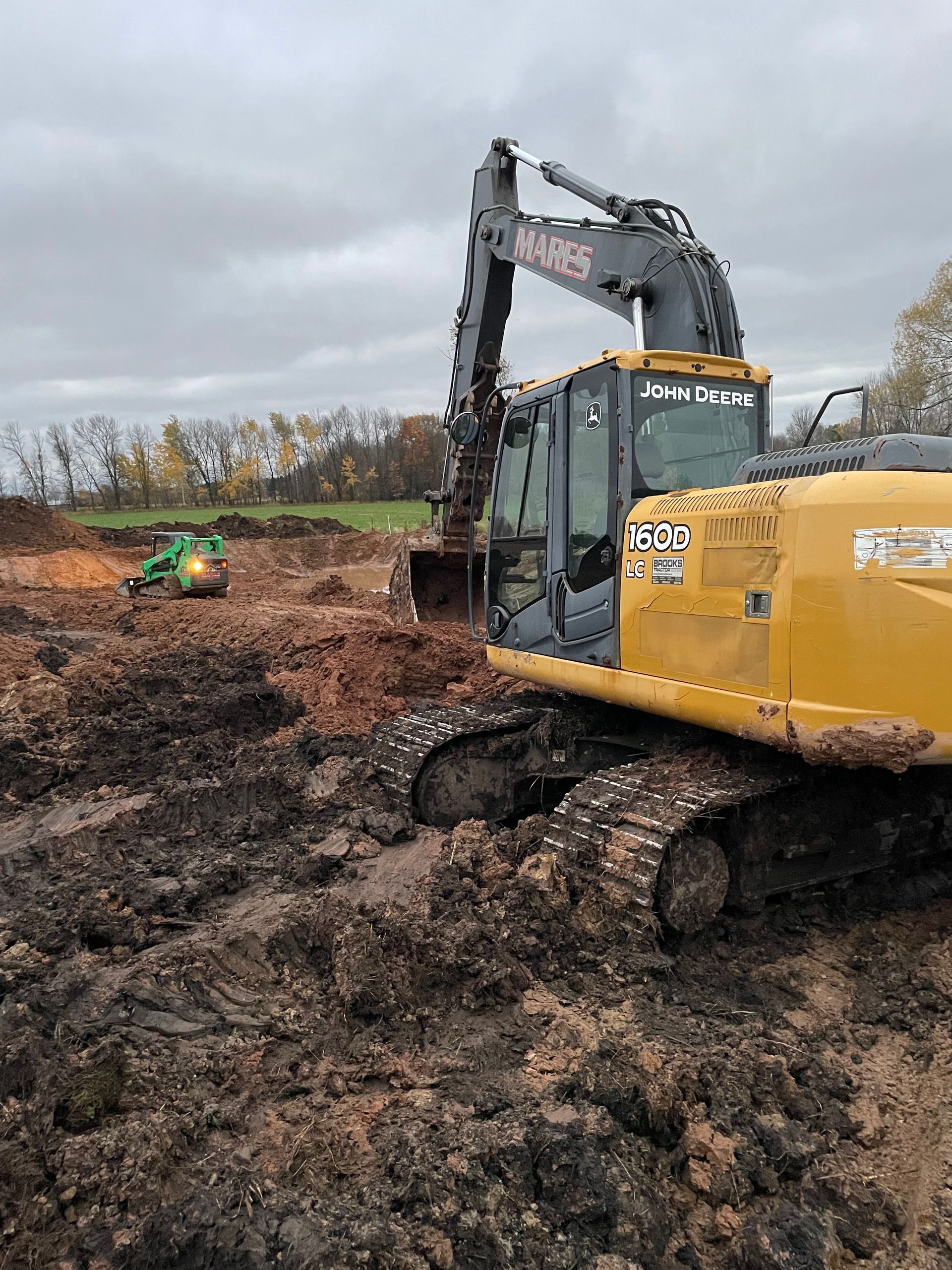 A yellow excavator is digging a hole in the mud.
