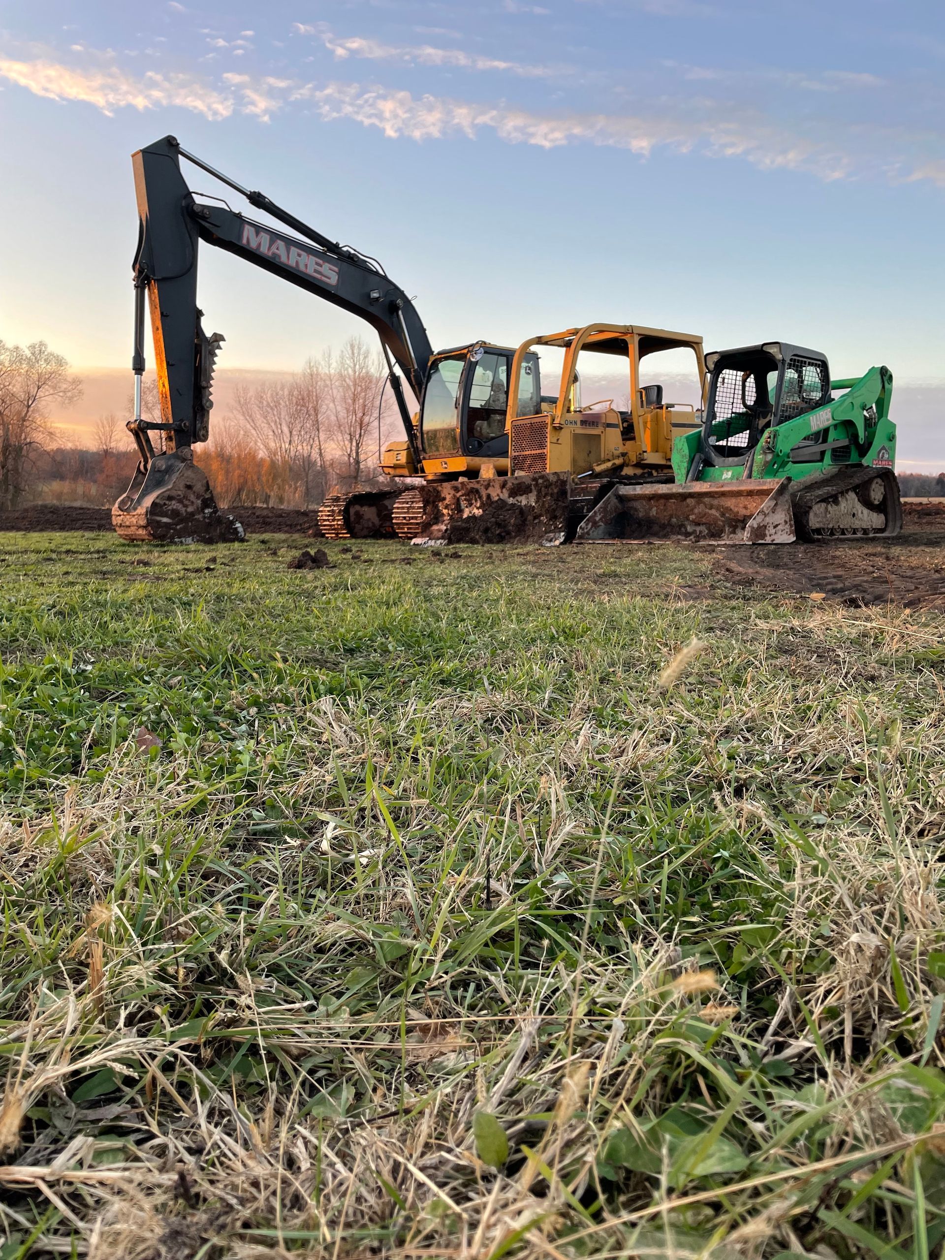 A group of construction vehicles are working in a field.