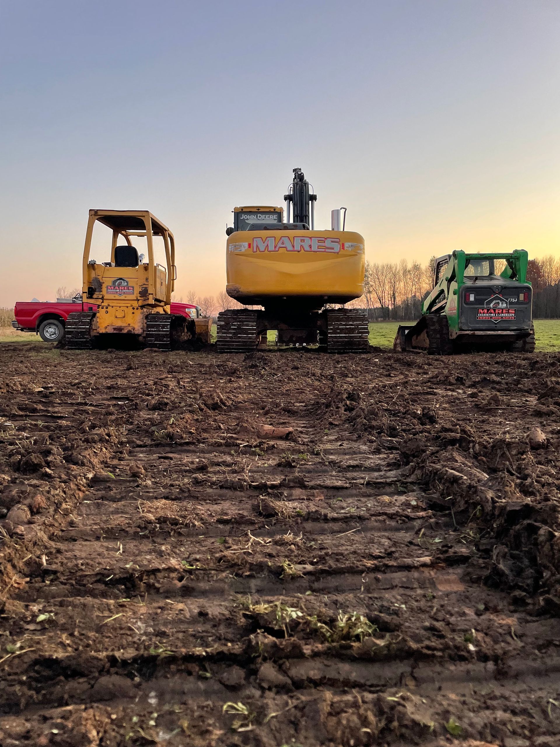 A bulldozer and a truck are parked in a dirt field.
