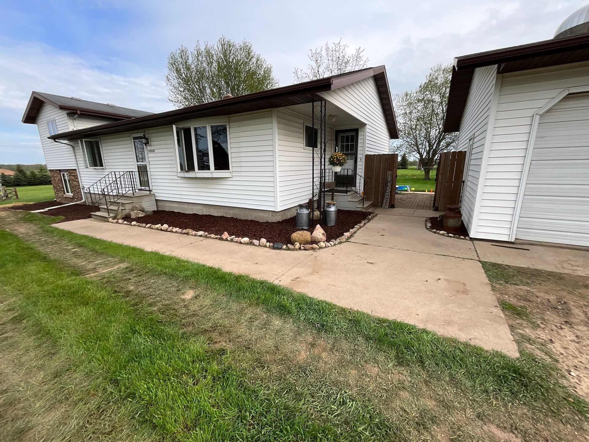 A white house with a concrete walkway leading to it.