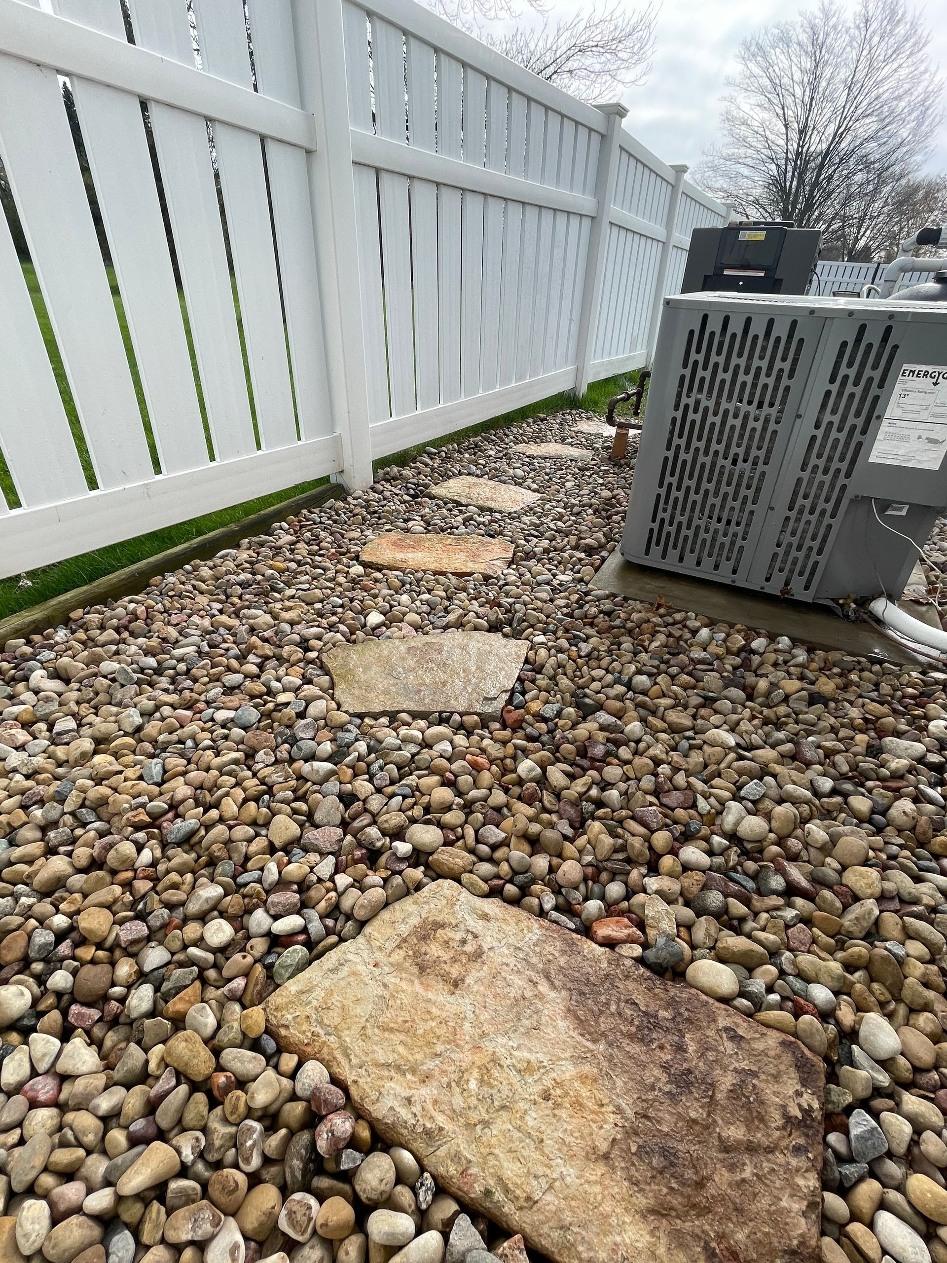 A white fence is surrounded by rocks and a bench.