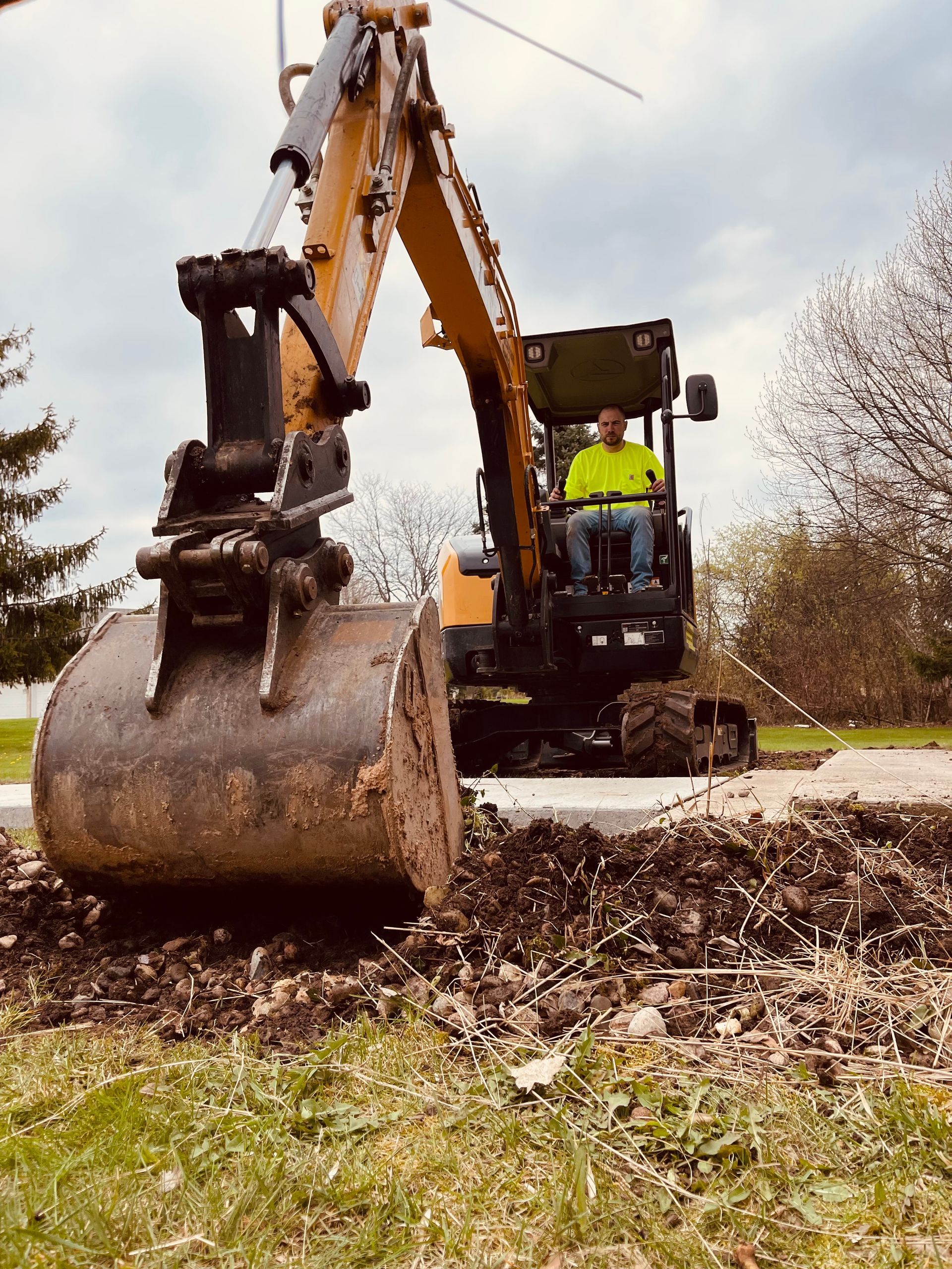 A man is driving an excavator on a dirt road.