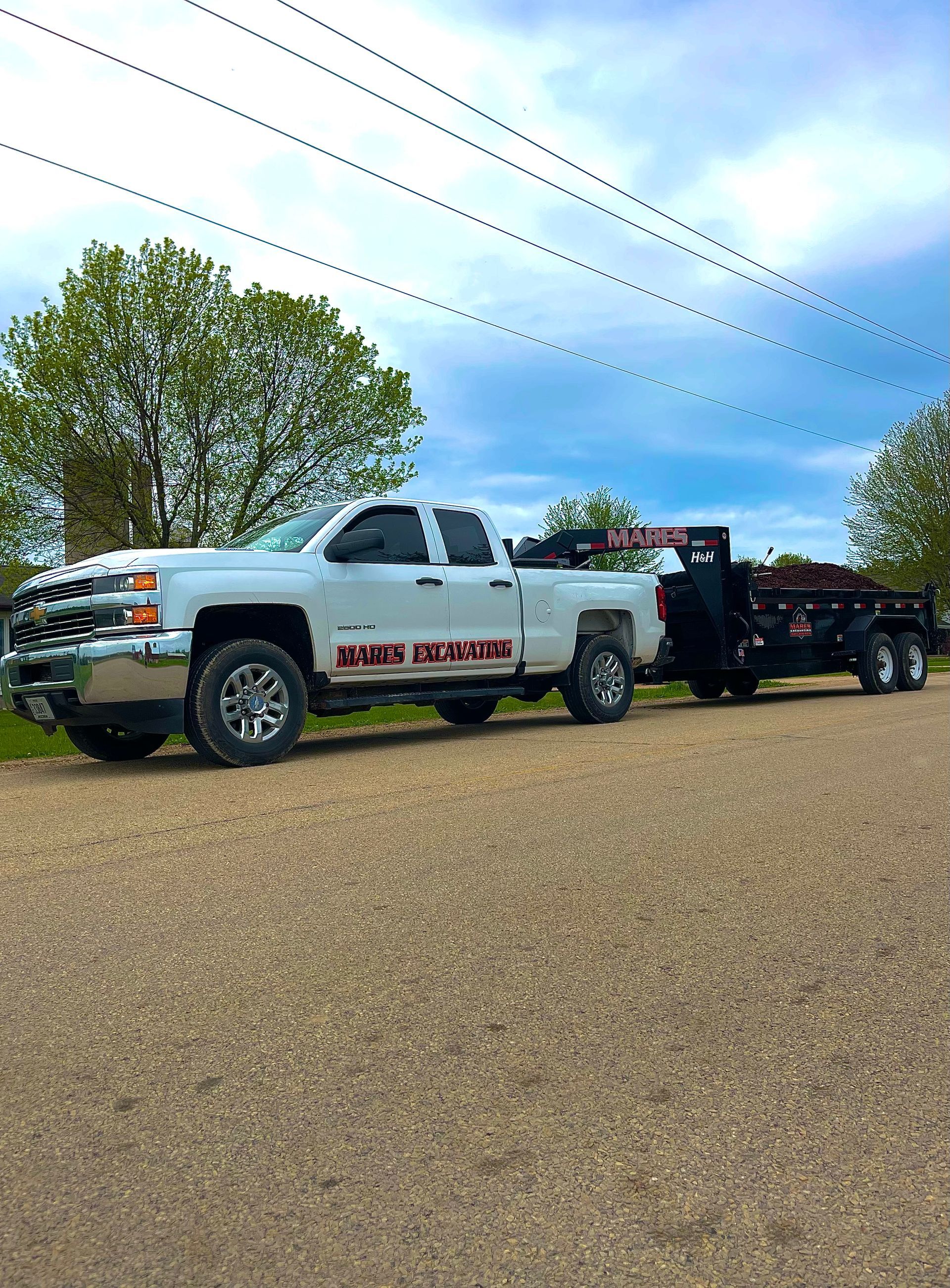 A white truck with a trailer attached to it is parked on a gravel road.
