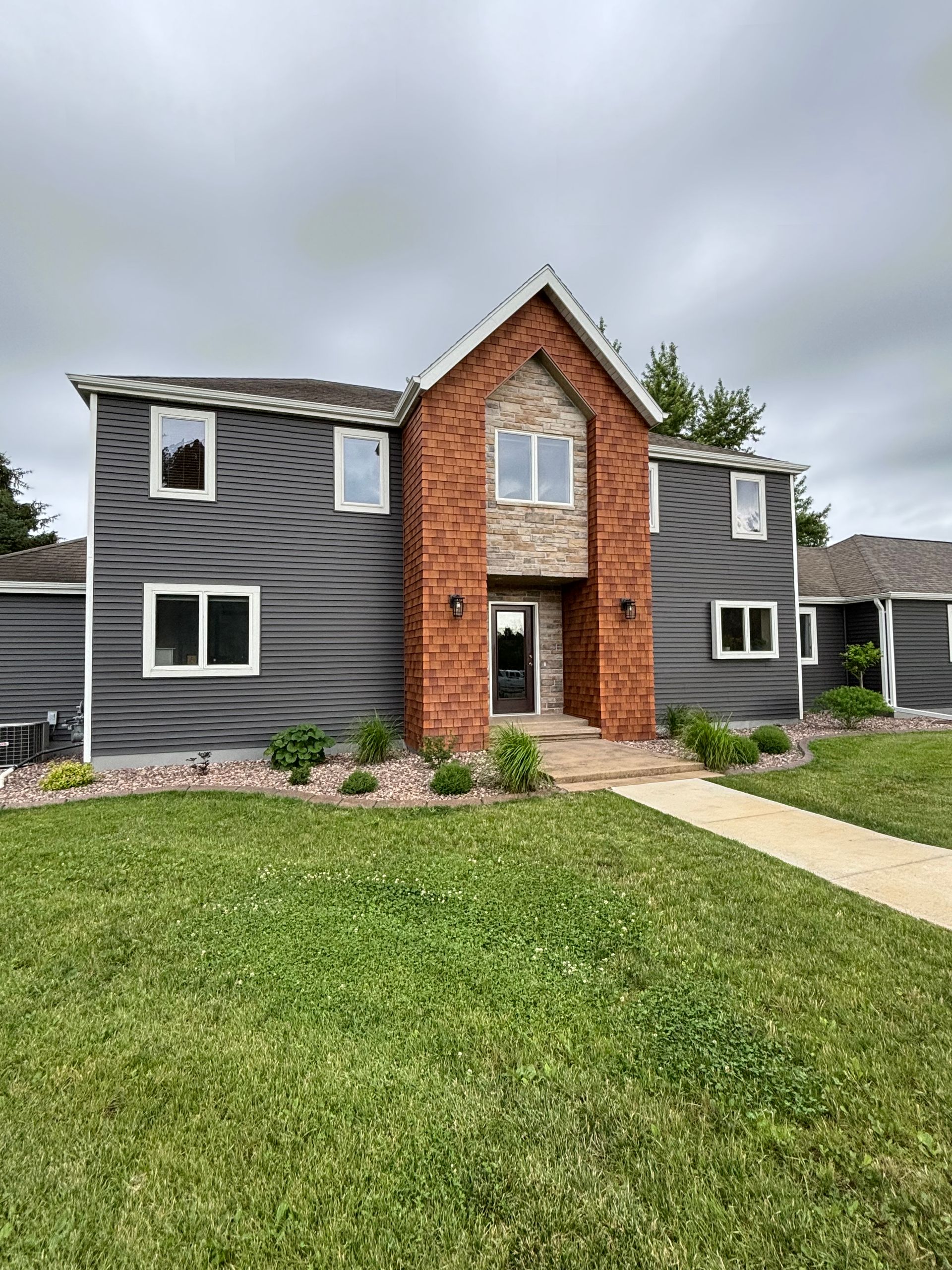 A large house with a lot of windows is sitting on top of a lush green lawn.