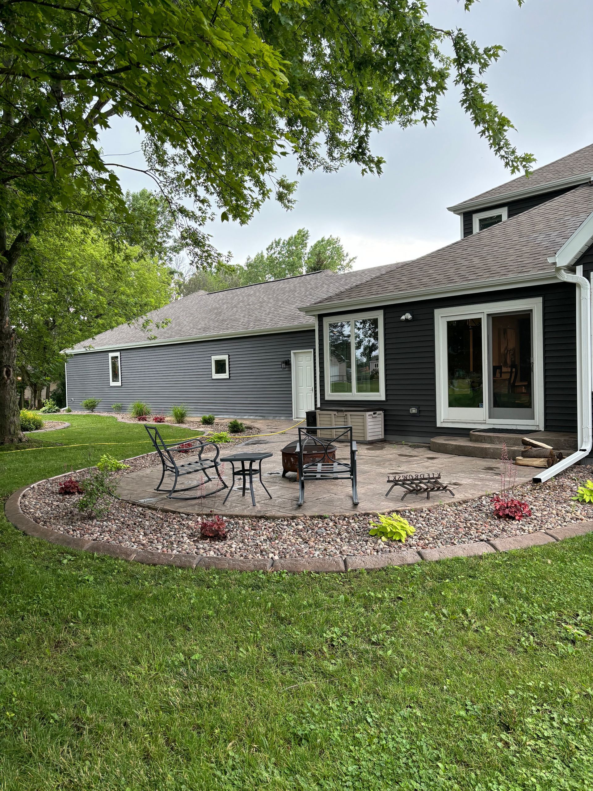A house with a patio and a fire pit in front of it.