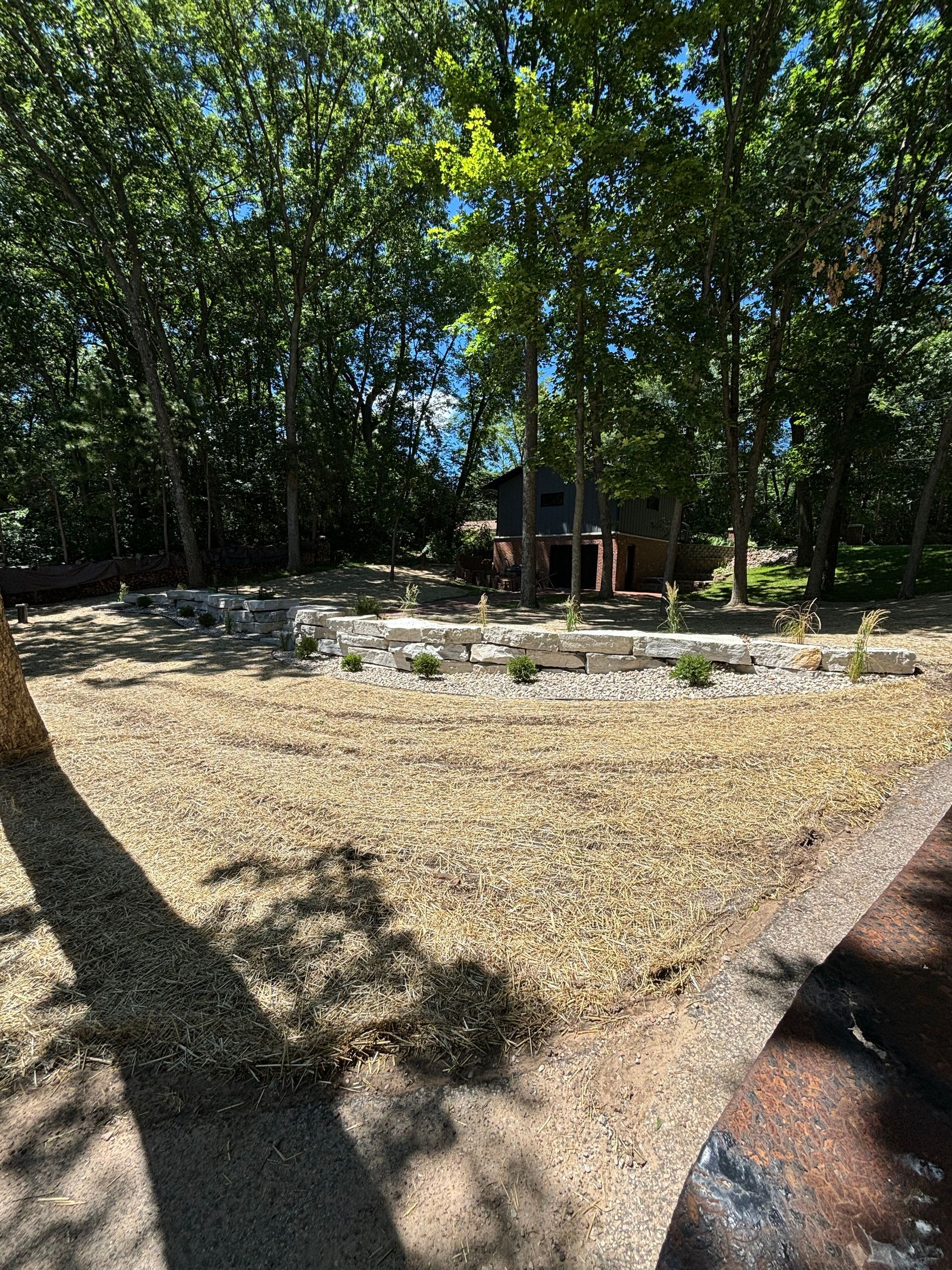 A dirt field with trees in the background and a house in the background.