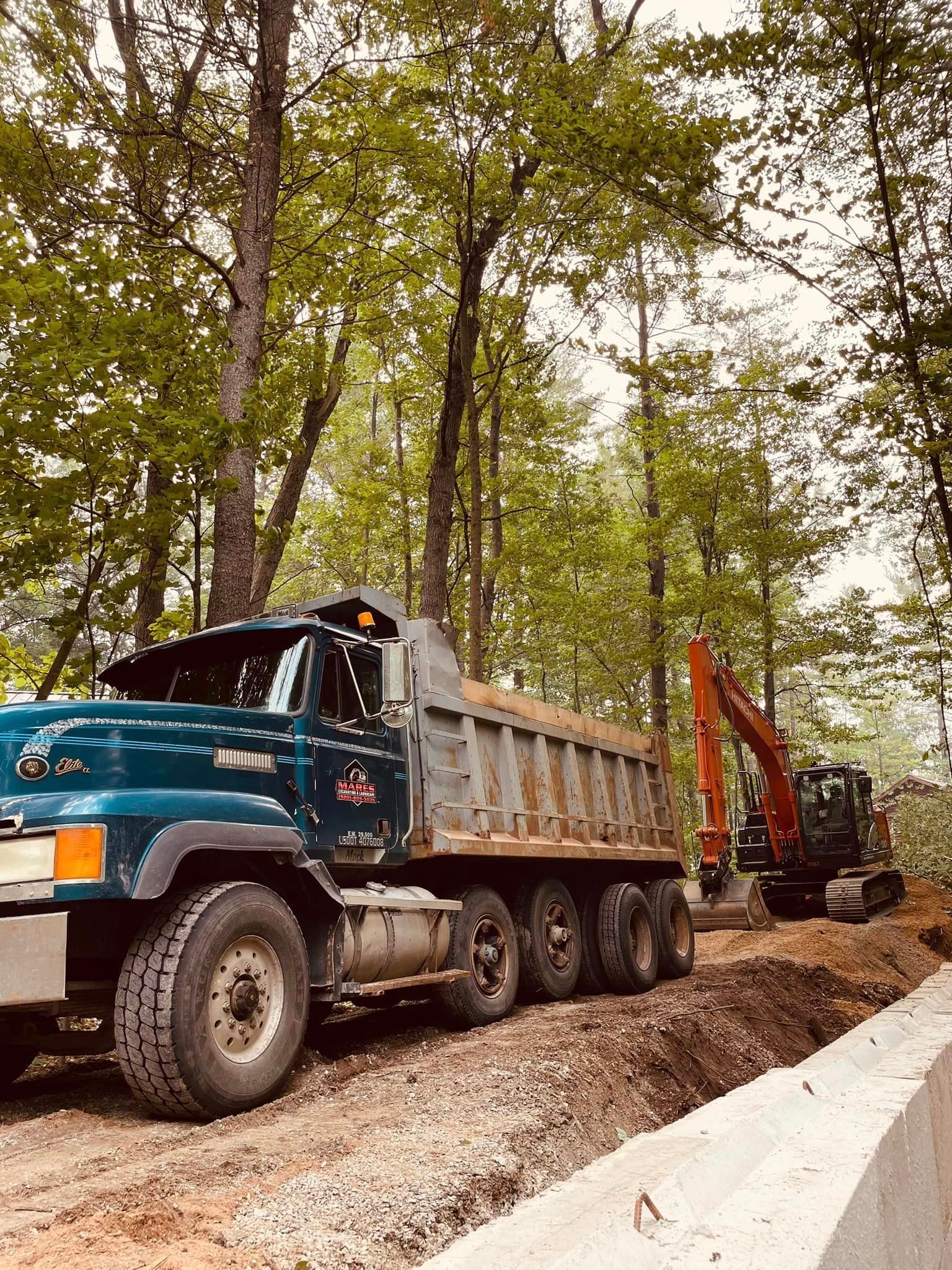 A dump truck is parked on a dirt road next to a bulldozer.