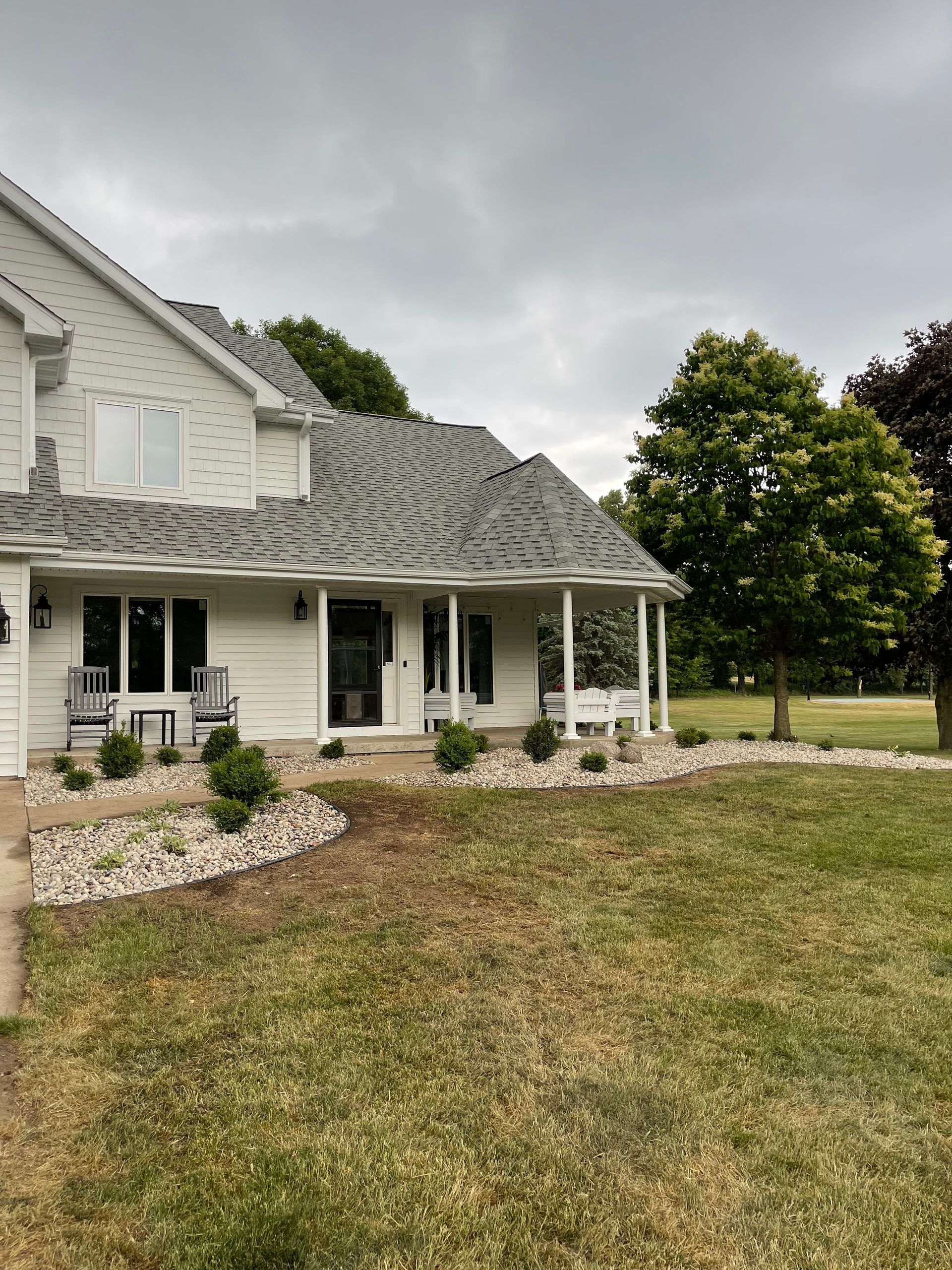 A white house with a gray roof and a porch.