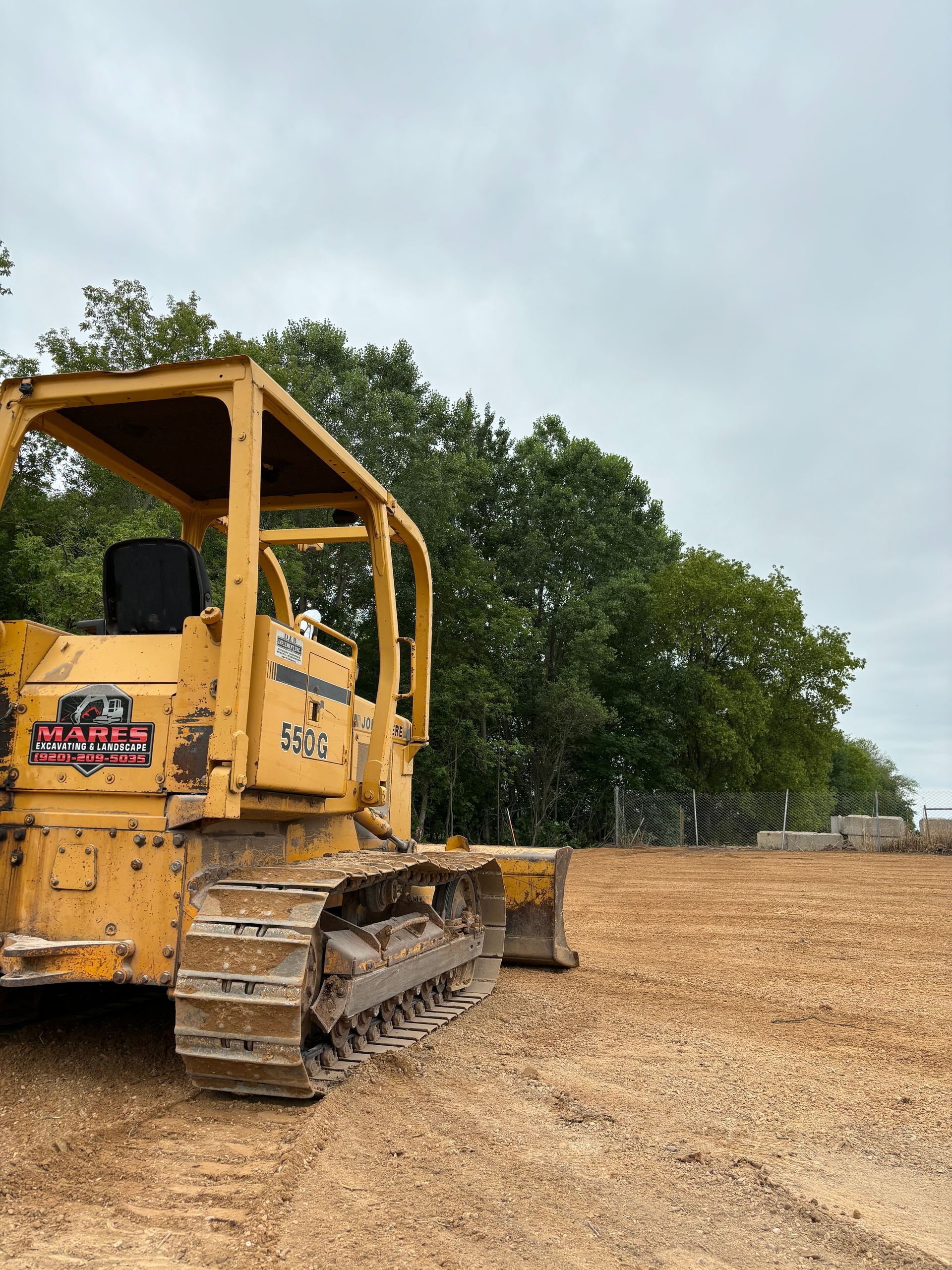 A yellow bulldozer is parked in a dirt field.