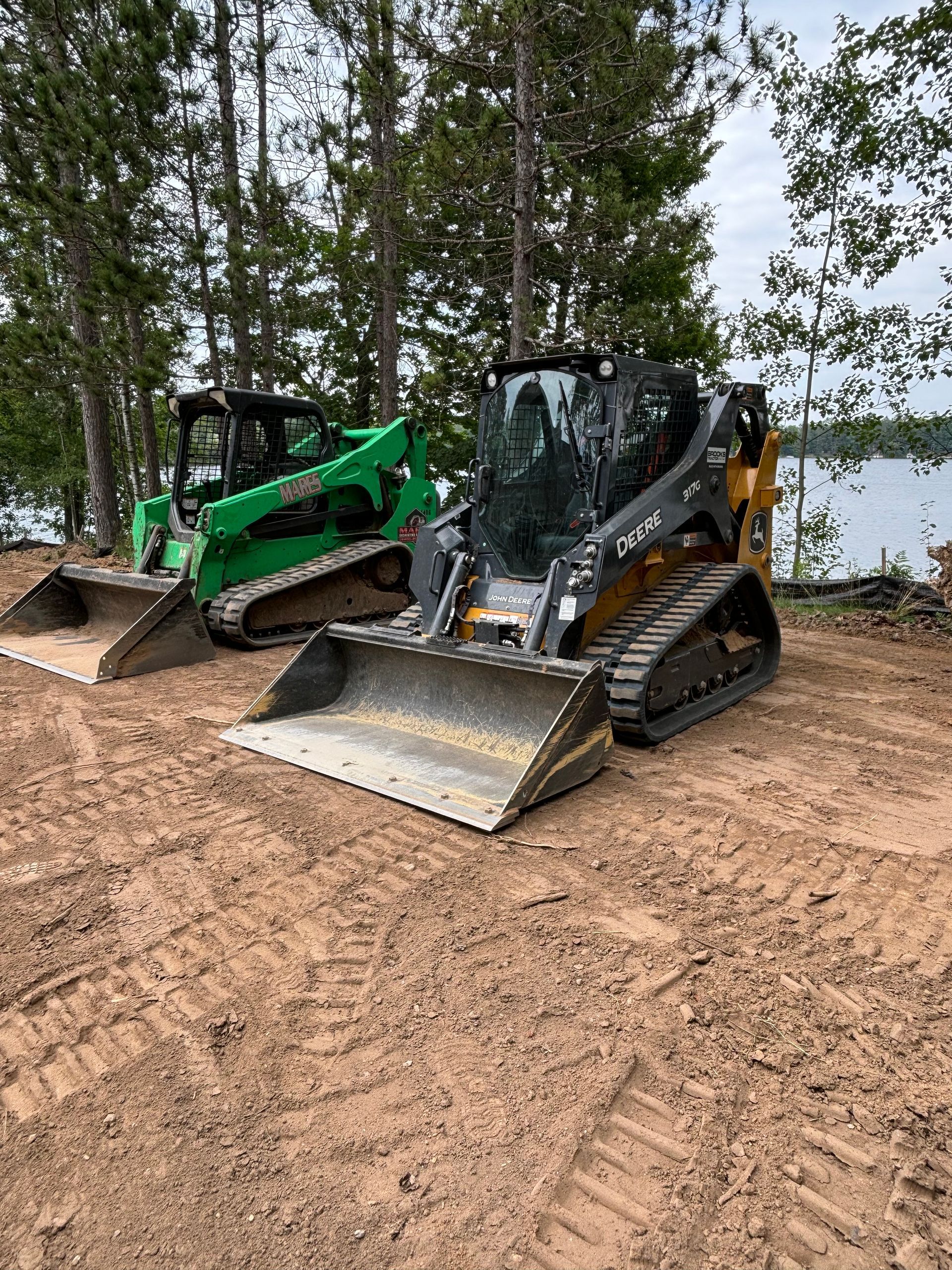 Two bulldozers are parked next to each other on a dirt field.