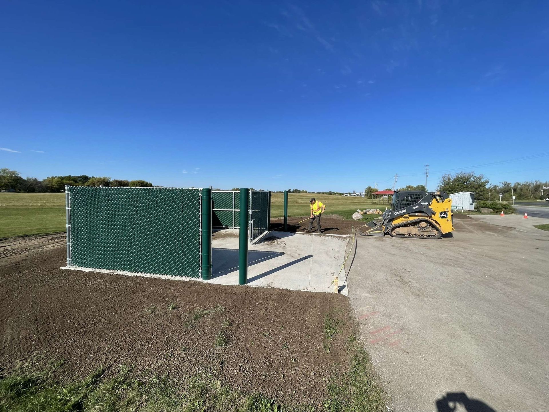 A construction site with a fence and a bulldozer in the background.