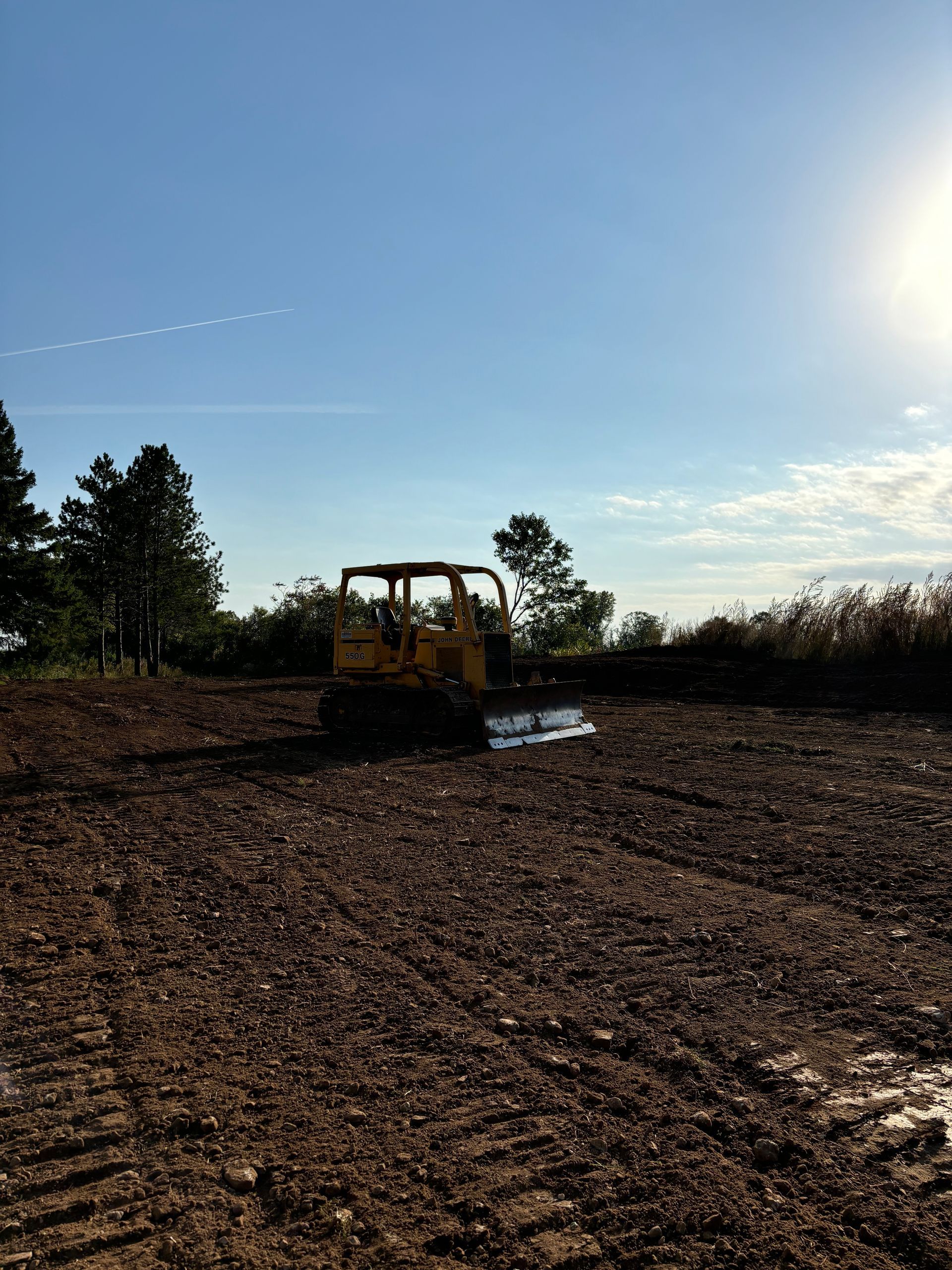 A yellow bulldozer is driving through a dirt field.