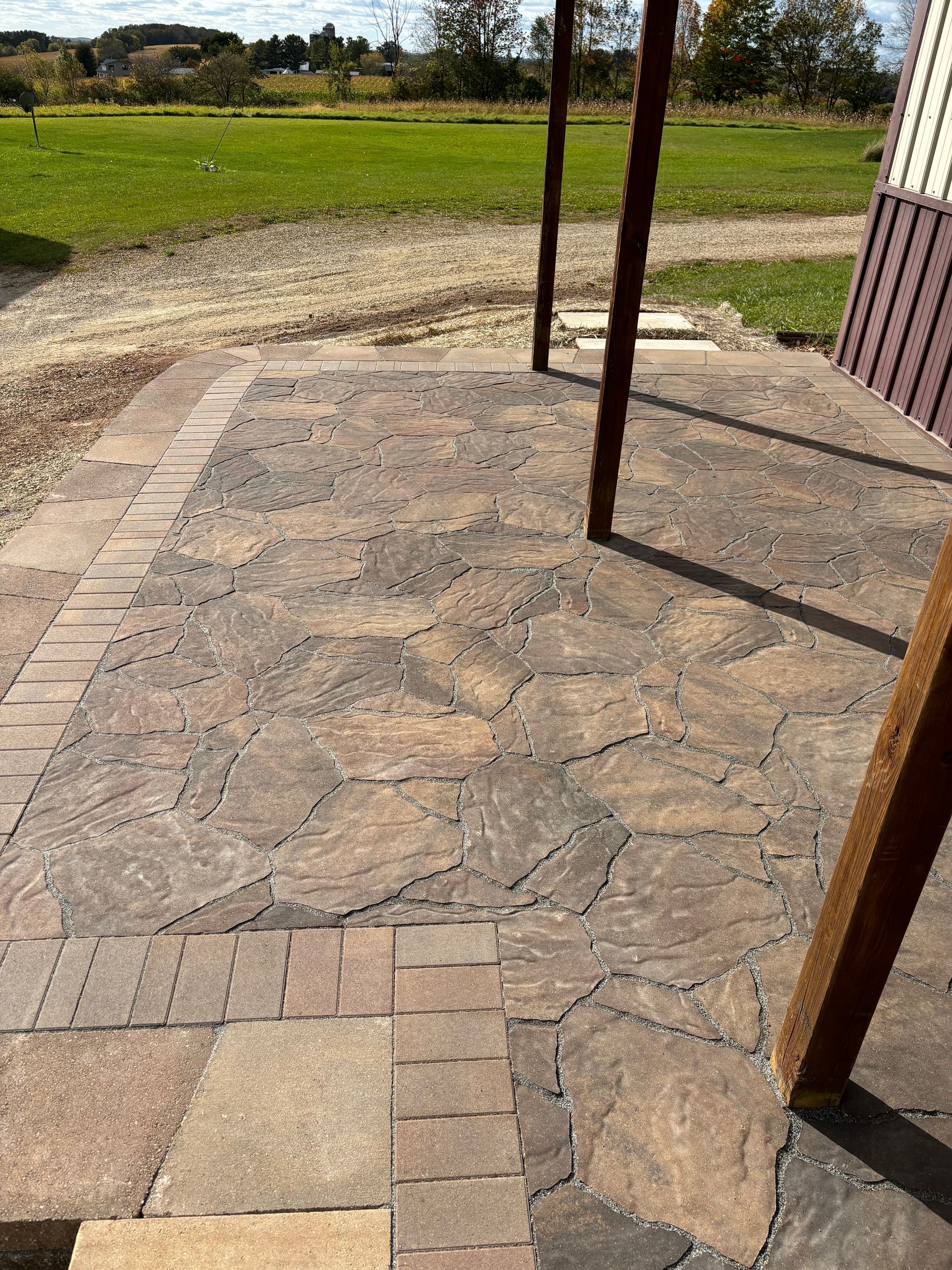 A brick patio with a covered area and a field in the background.