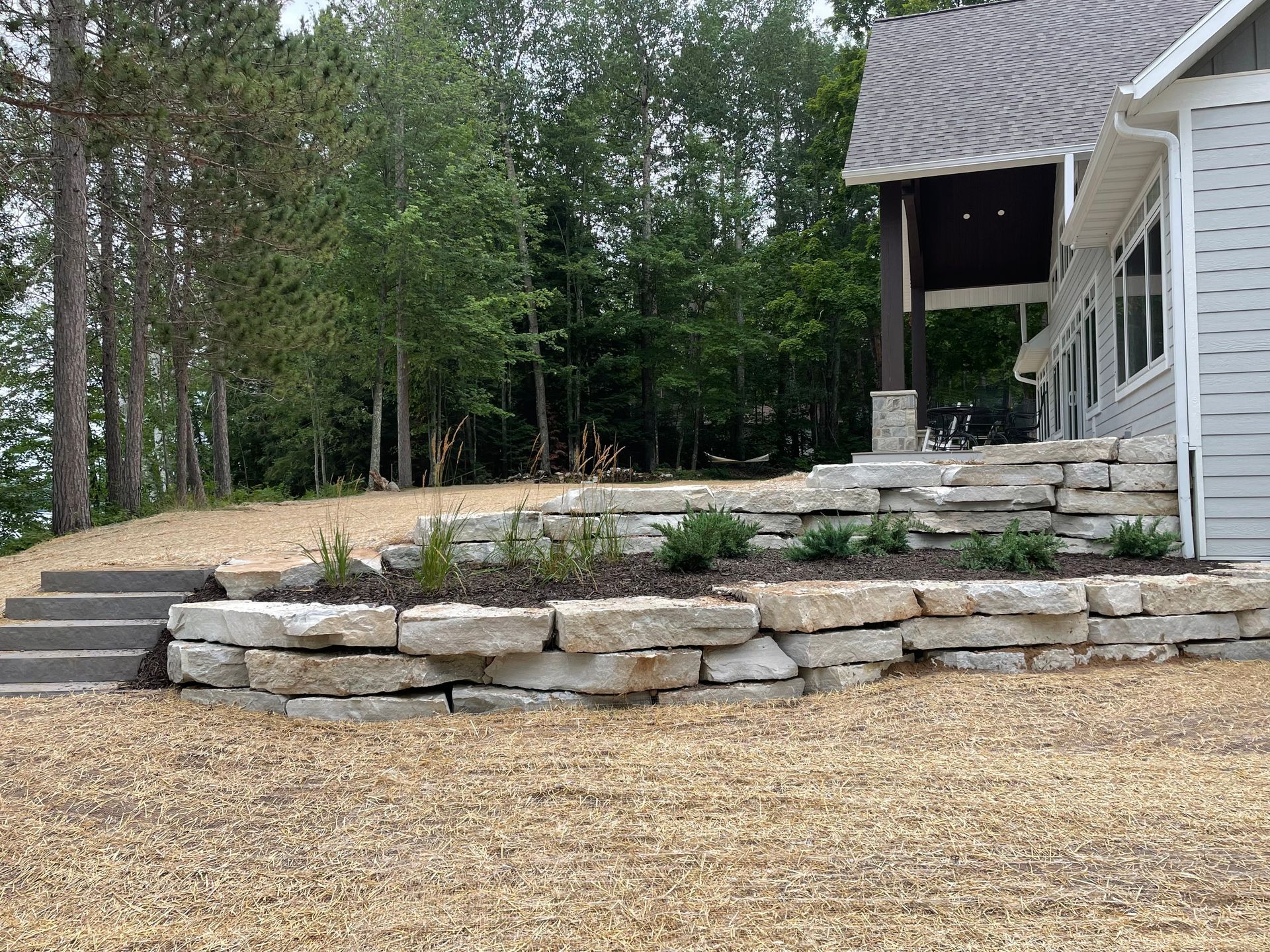 A house with a stone wall and stairs in front of it.