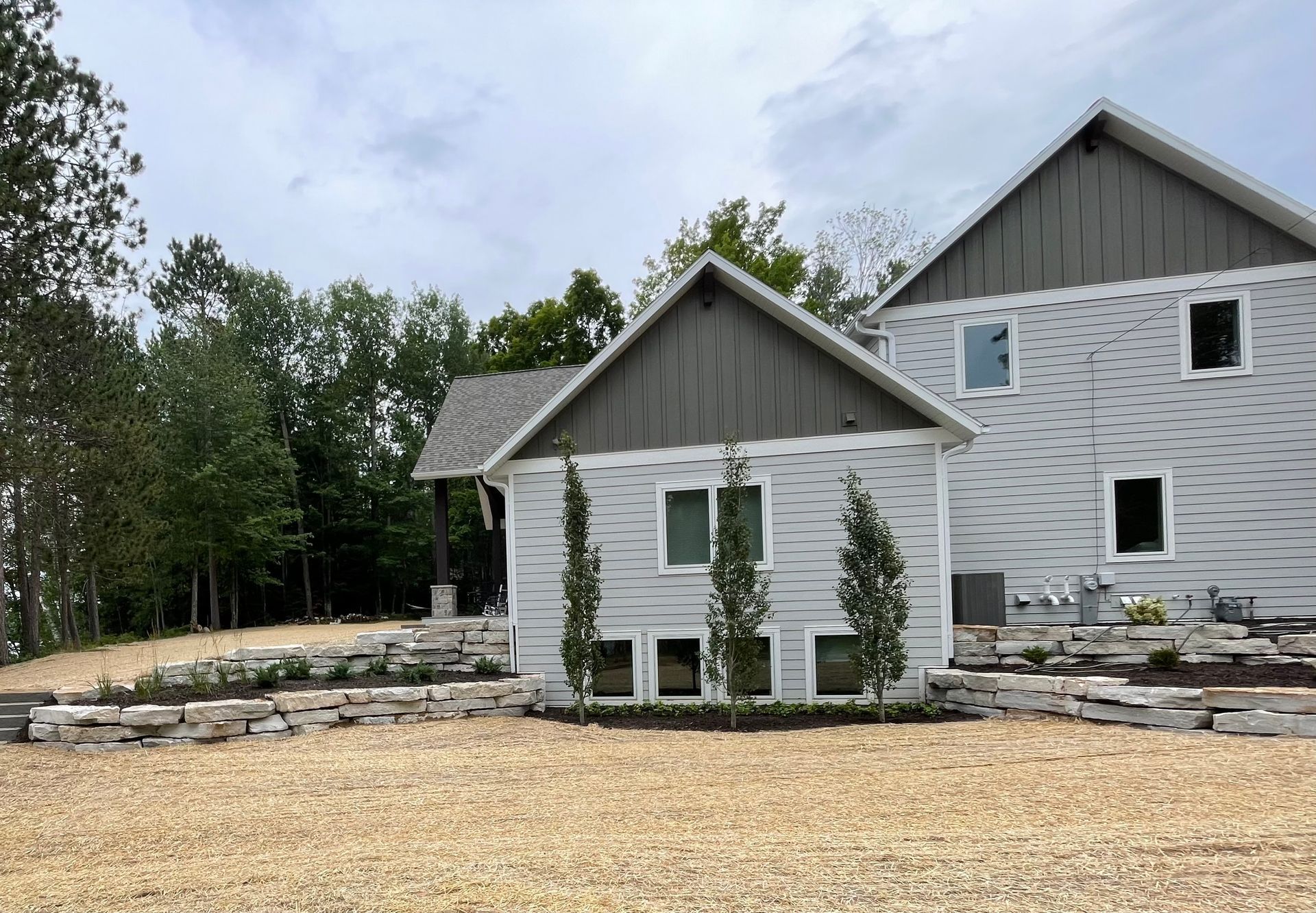 A large white house with a gray roof is sitting on top of a dirt hill.