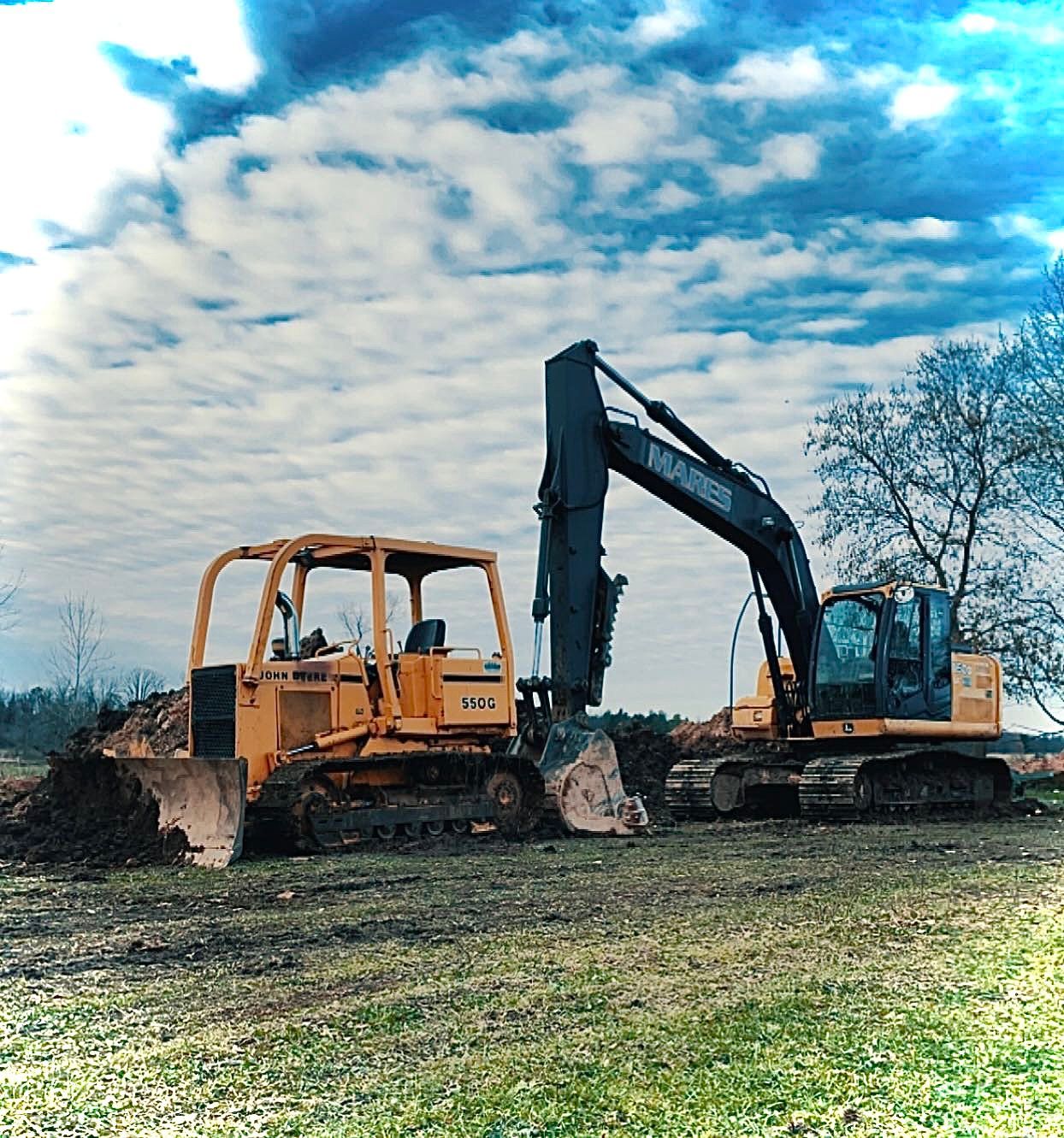 A bulldozer and an excavator are parked in a grassy field