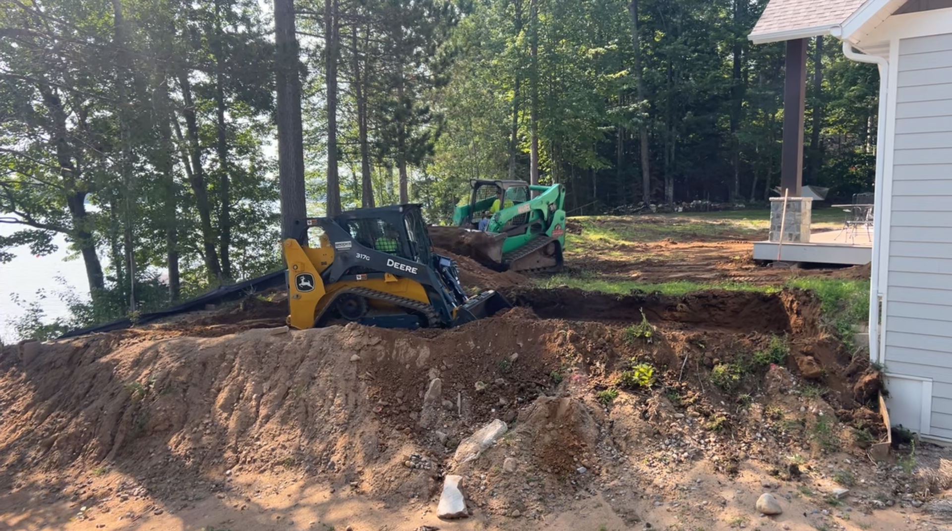 A tractor is digging a hole in the ground in front of a house.