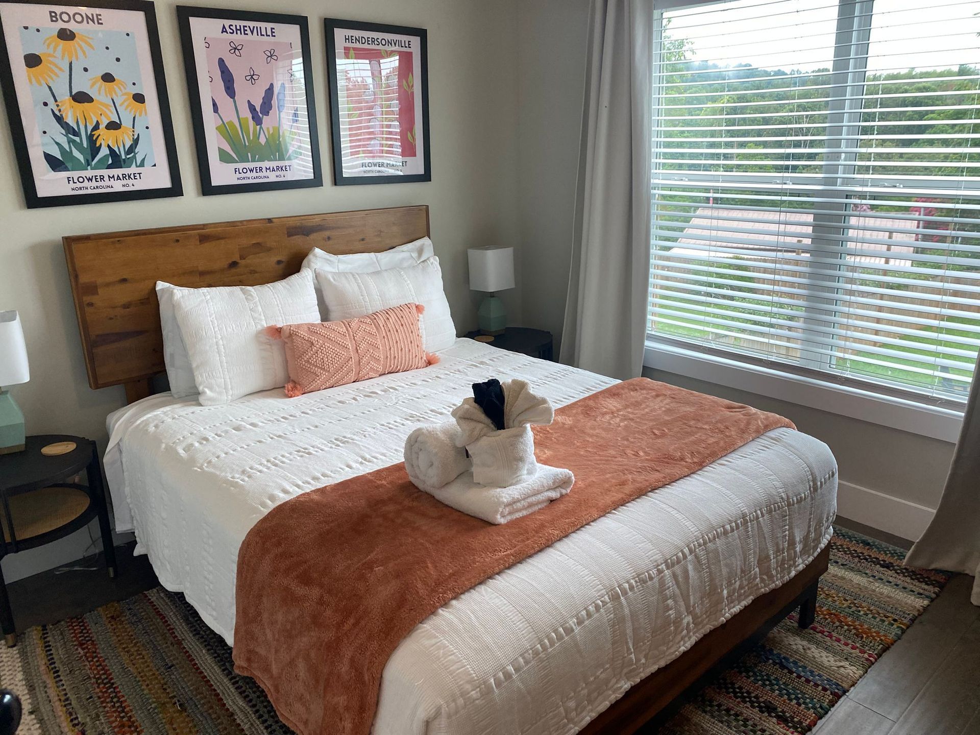 Bedroom with bed, decorative art, window. White bedding, orange accents.