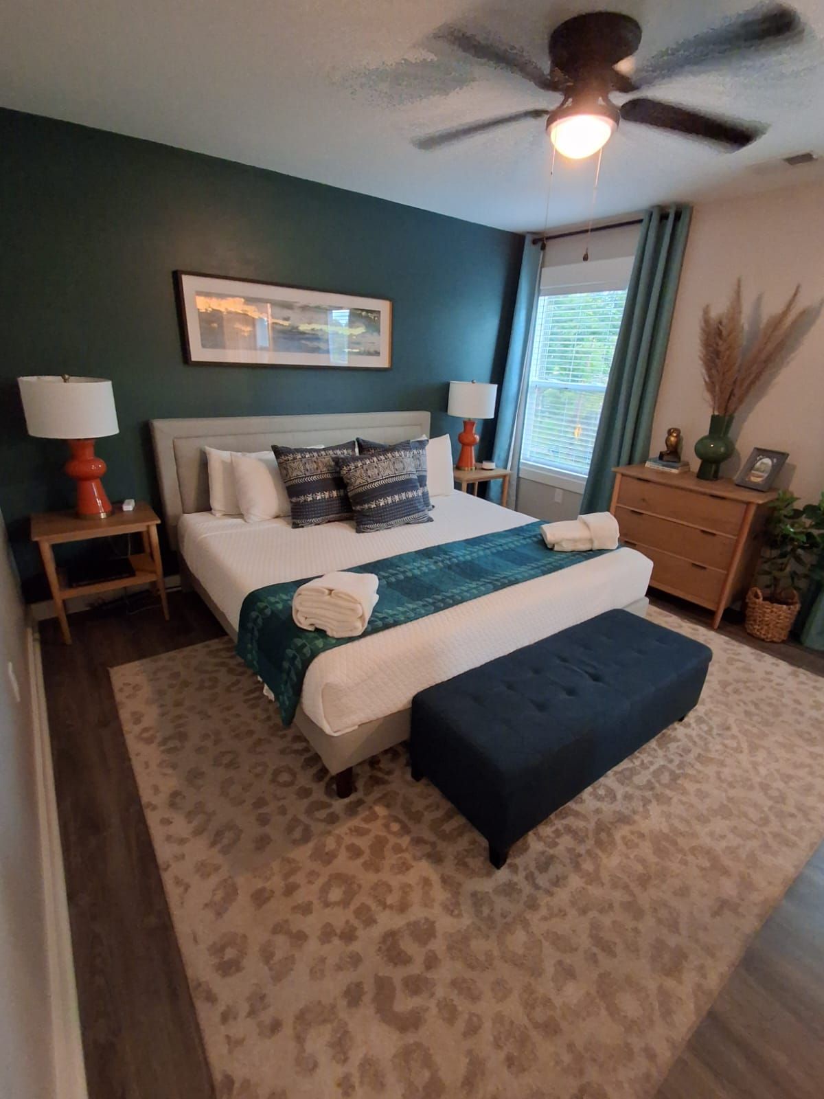 Cozy bedroom with a king bed, teal accent wall, and patterned rug.