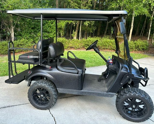 A black golf cart is parked on the side of the road